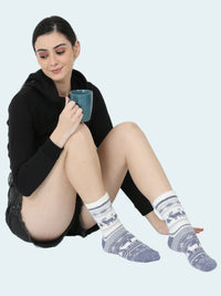 Woman wearing patterned socks sitting on the floor with a mug.