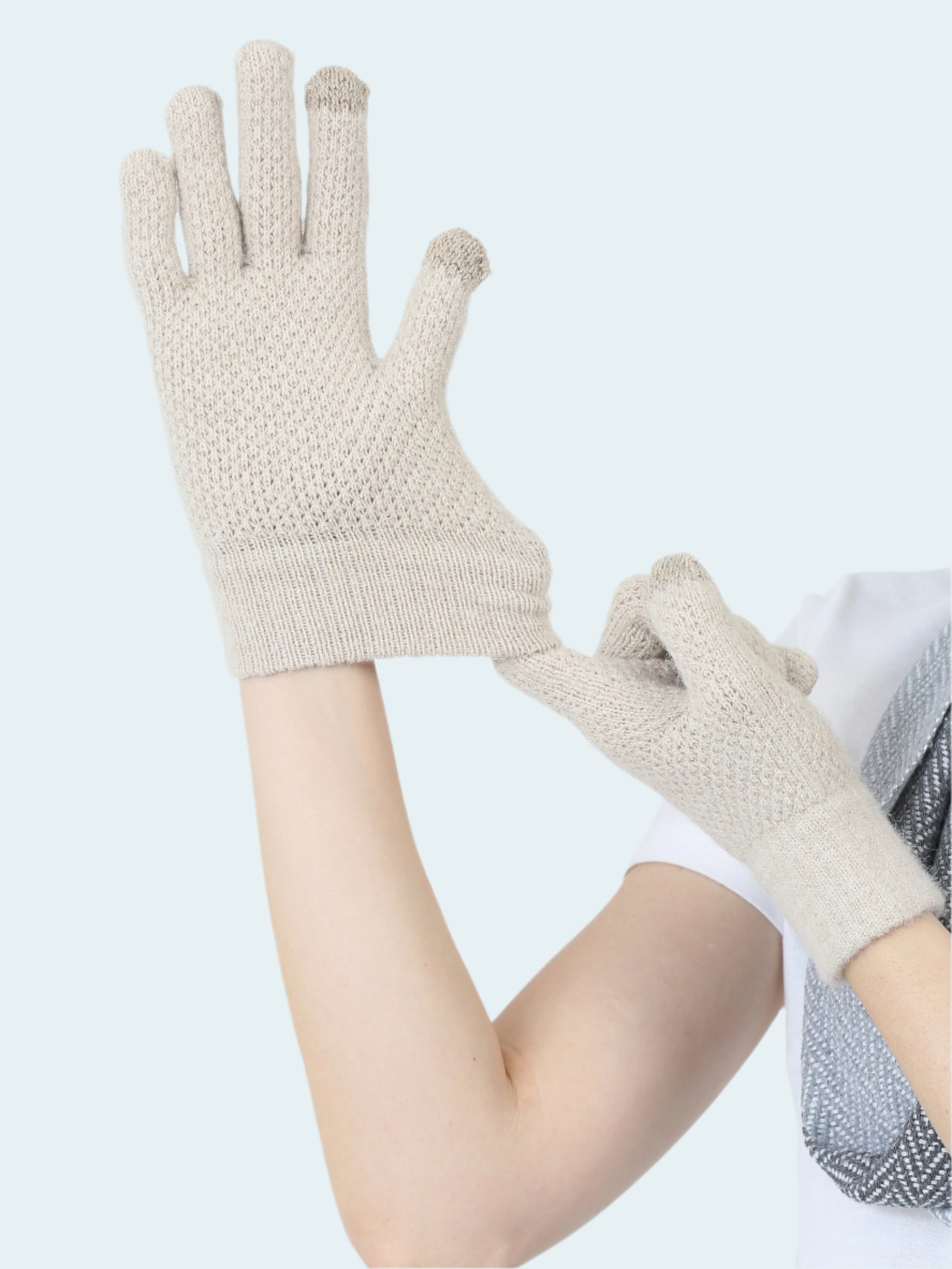 Pair of beige gloves held by a person on a light gray background