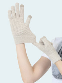 Pair of beige gloves held by a person on a light gray background