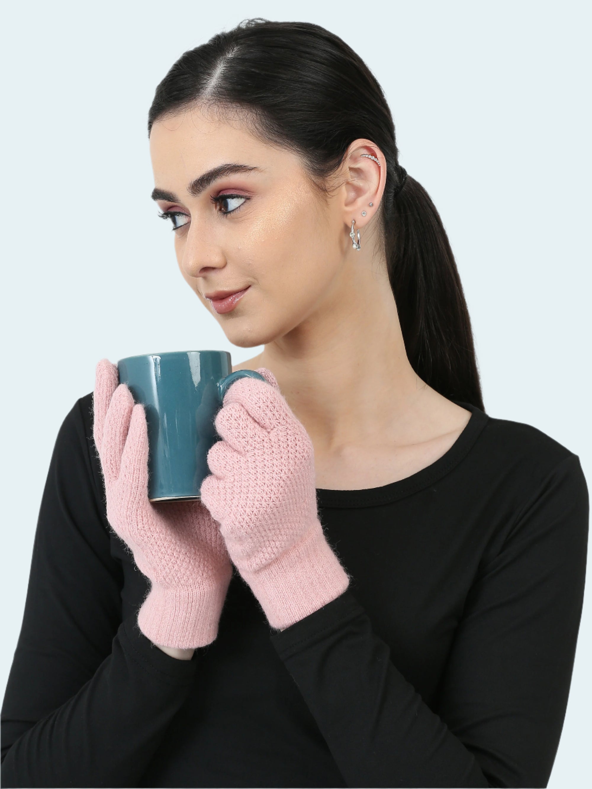 Woman wearing pink gloves holding a blue mug against a white background