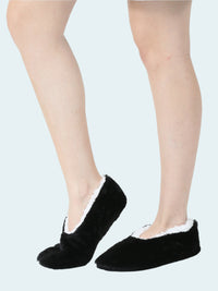 A pair of black faux fur slipper socks worn on female legs.