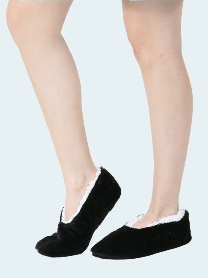 A pair of black faux fur slipper socks worn on female legs.