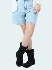 Person wearing black chenille socks with a white background