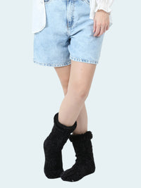 Person wearing black chenille socks with a white background