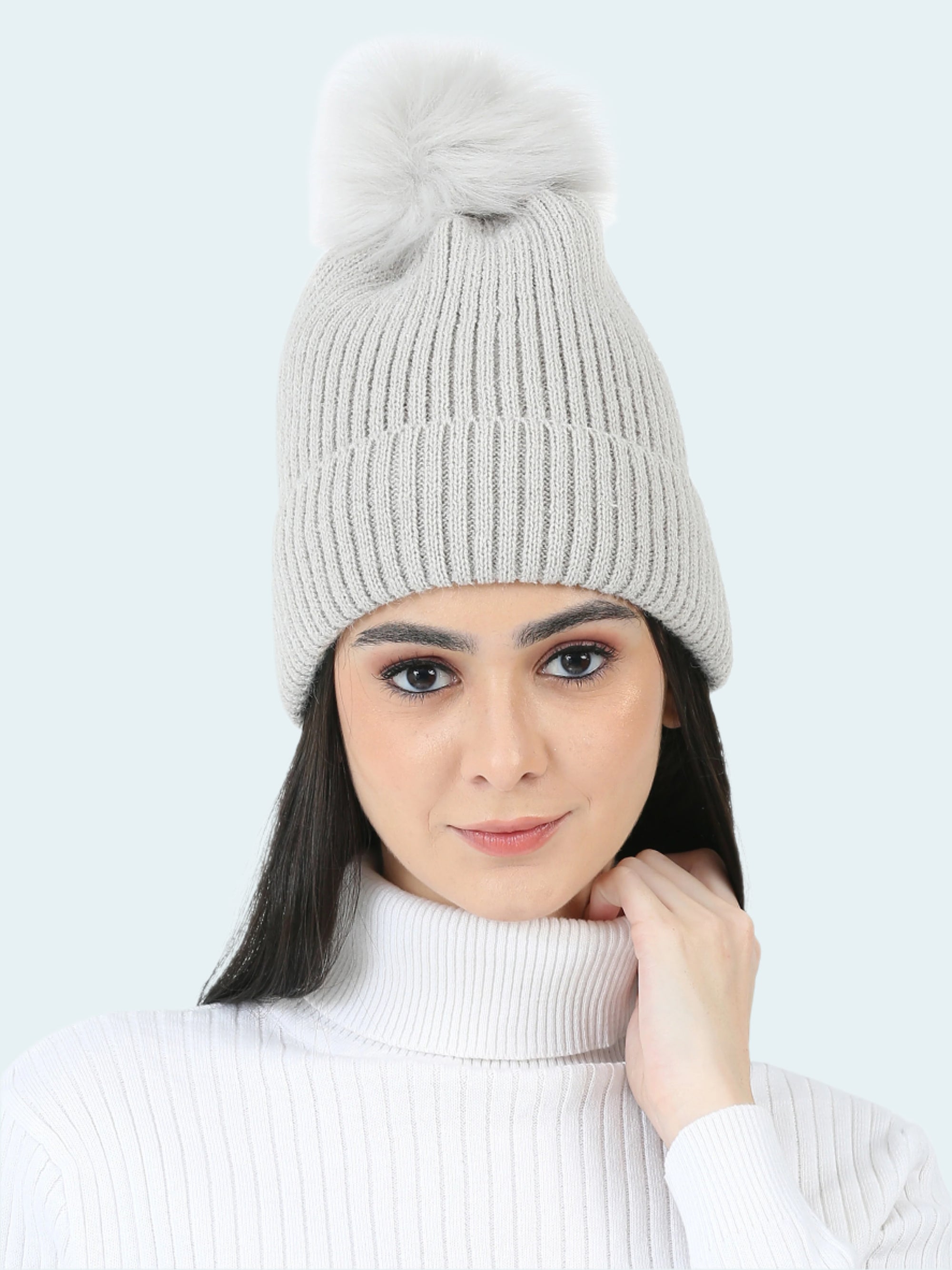 Woman wearing a gray knit beanie with a pom-pom on a white background