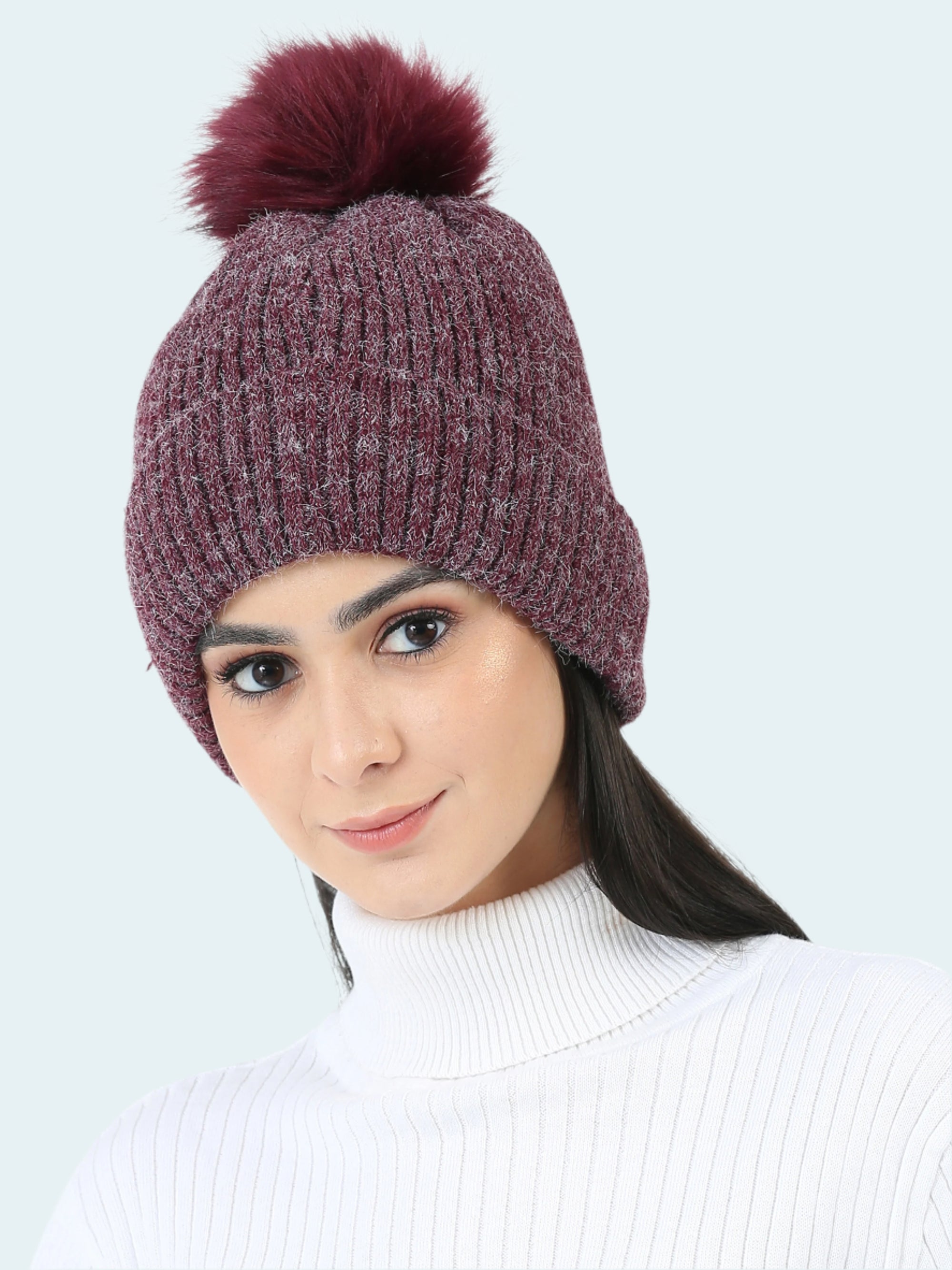 Woman wearing a maroon knit beanie with a pom-pom on a white background