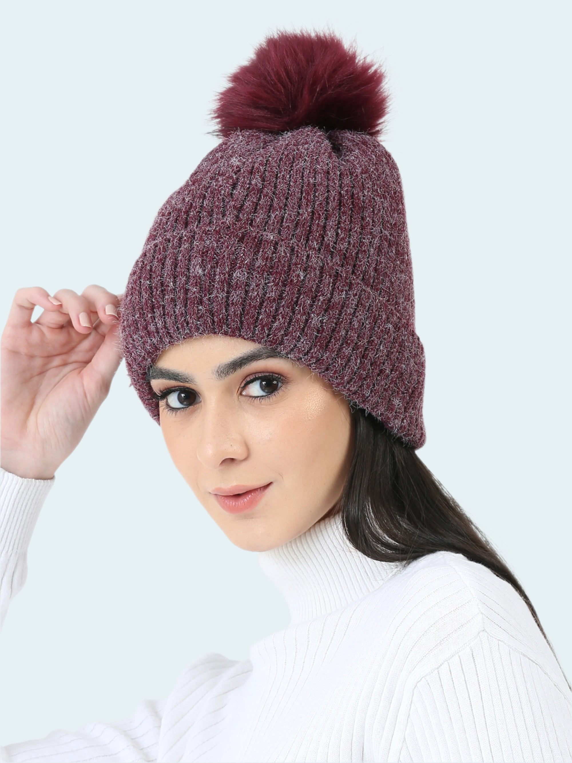 Woman wearing a purple knit beanie with a pom-pom on a white background