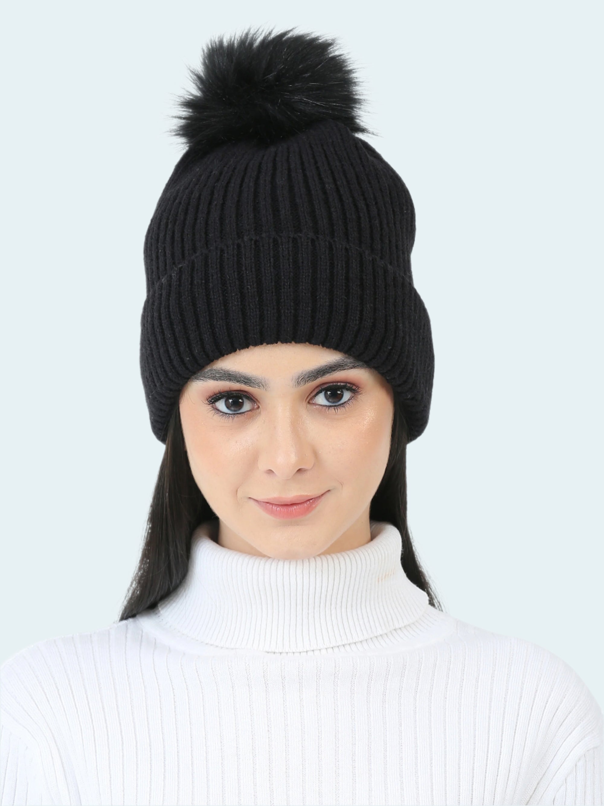 Woman wearing a black knit beanie with a pom-pom on a white background