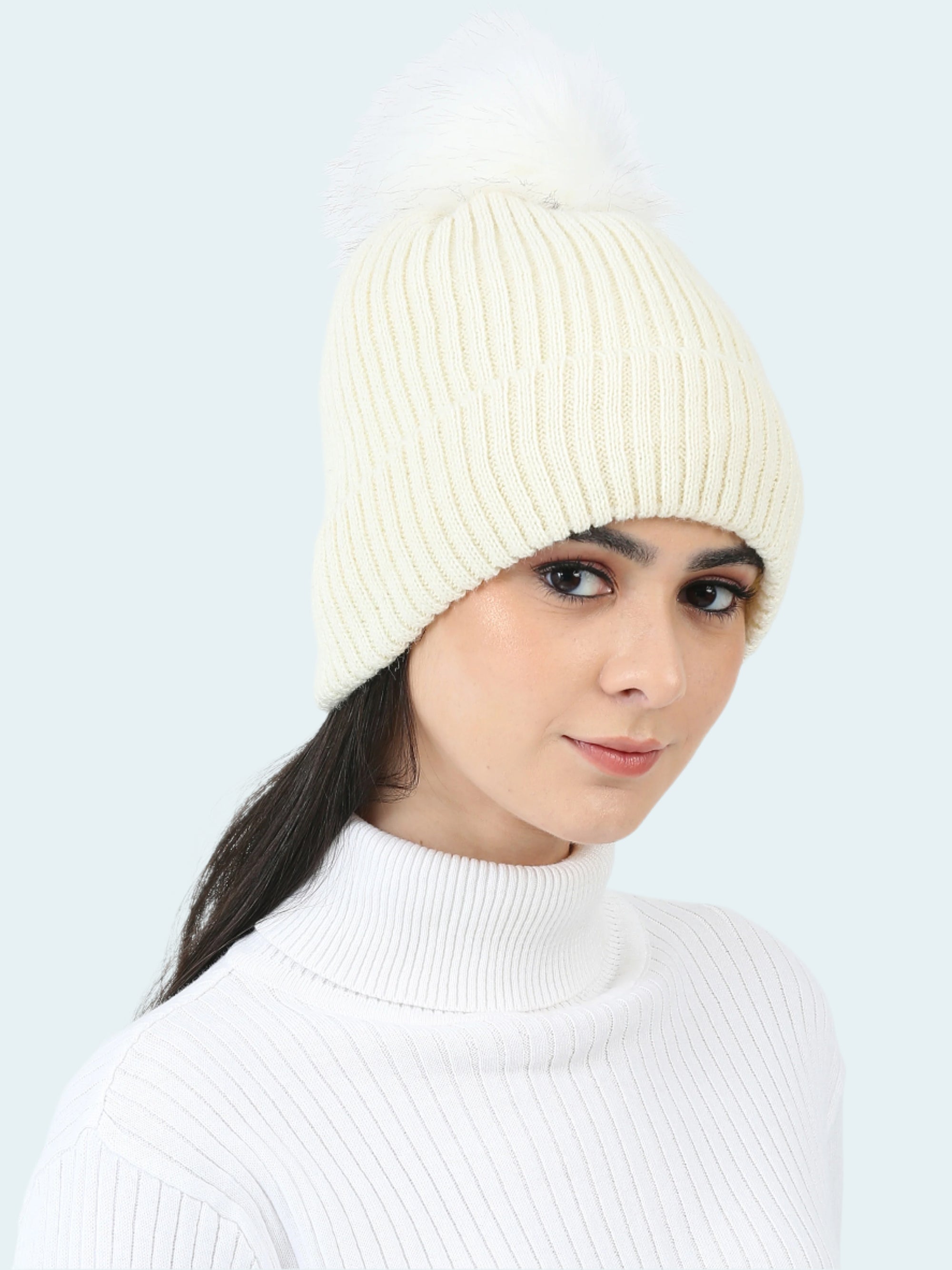 Woman wearing a white knit beanie and turtleneck against a light gray background