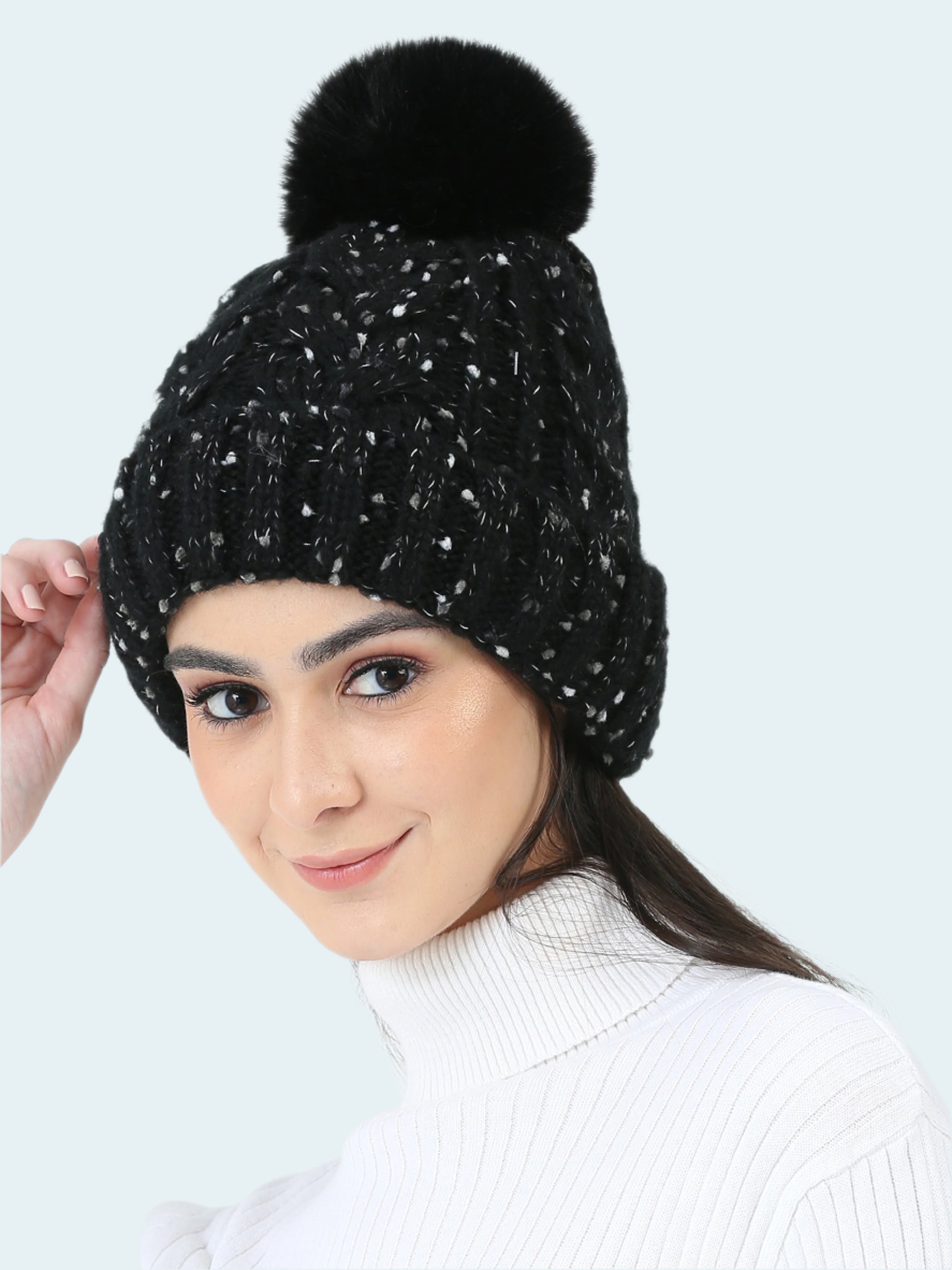 Woman wearing a black beanie with a pom-pom on a white background