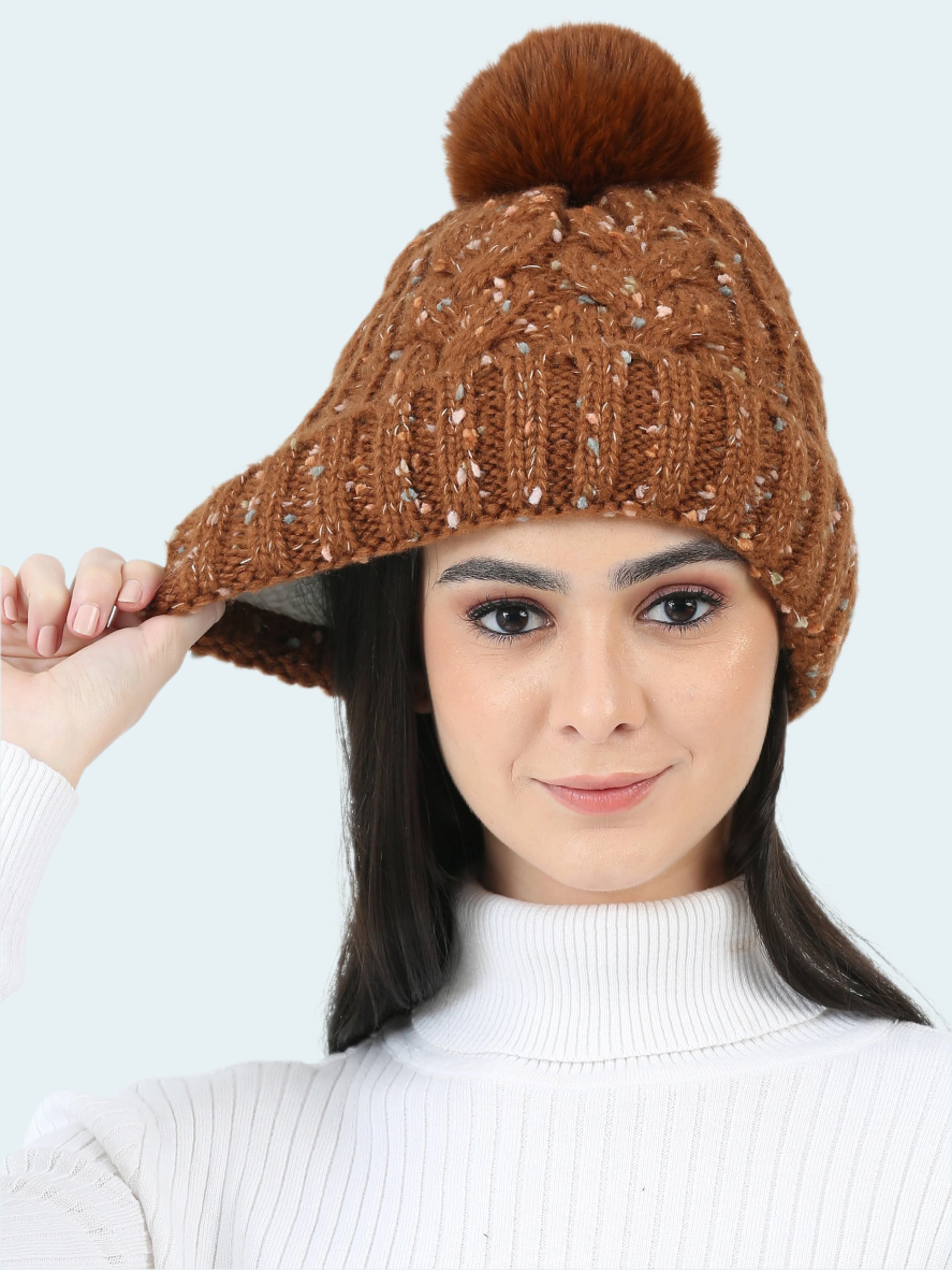 Woman wearing a brown knitted beanie with a pom-pom on a white background