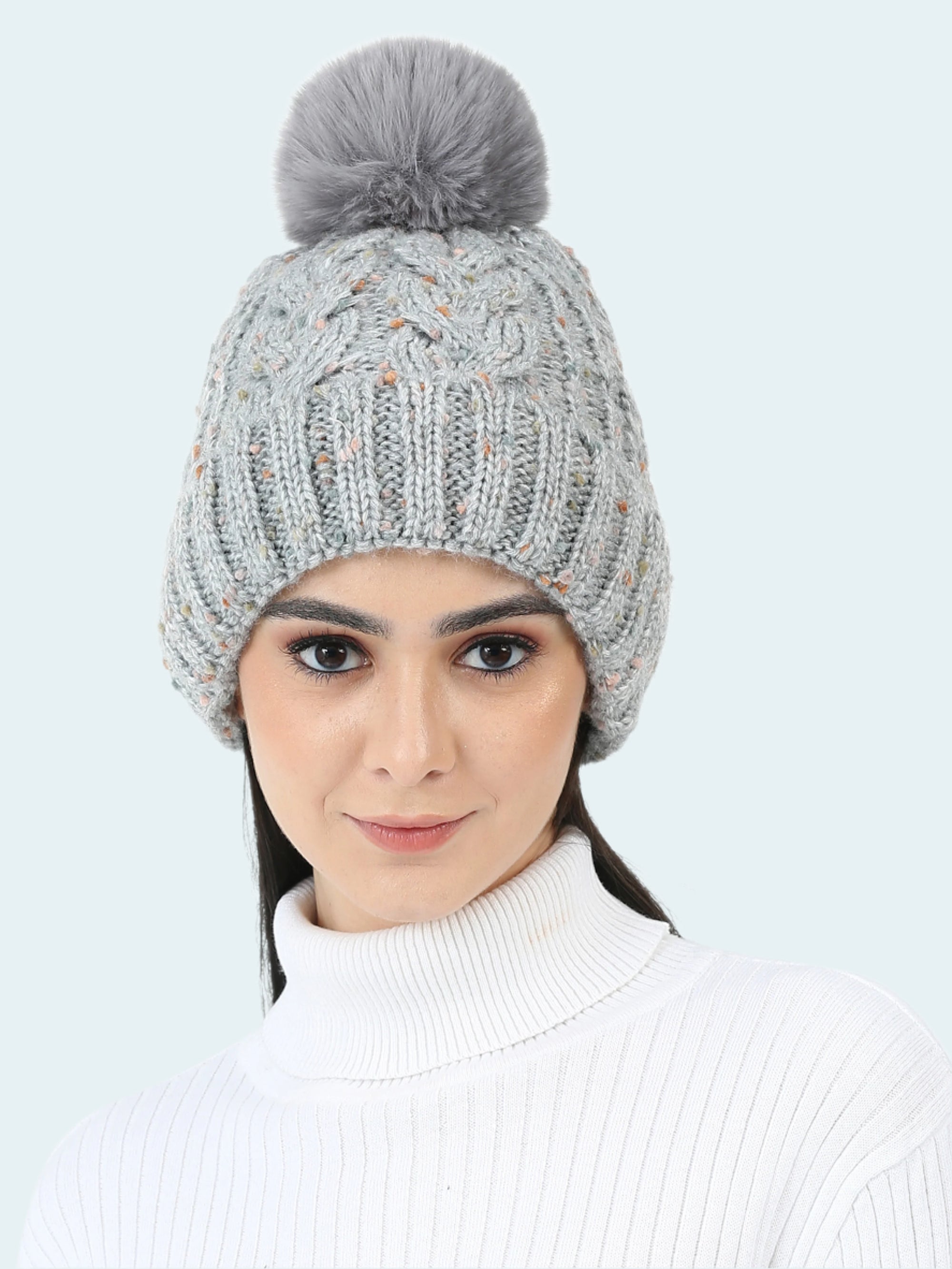 Woman wearing a gray knitted beanie with a pom-pom on a white background
