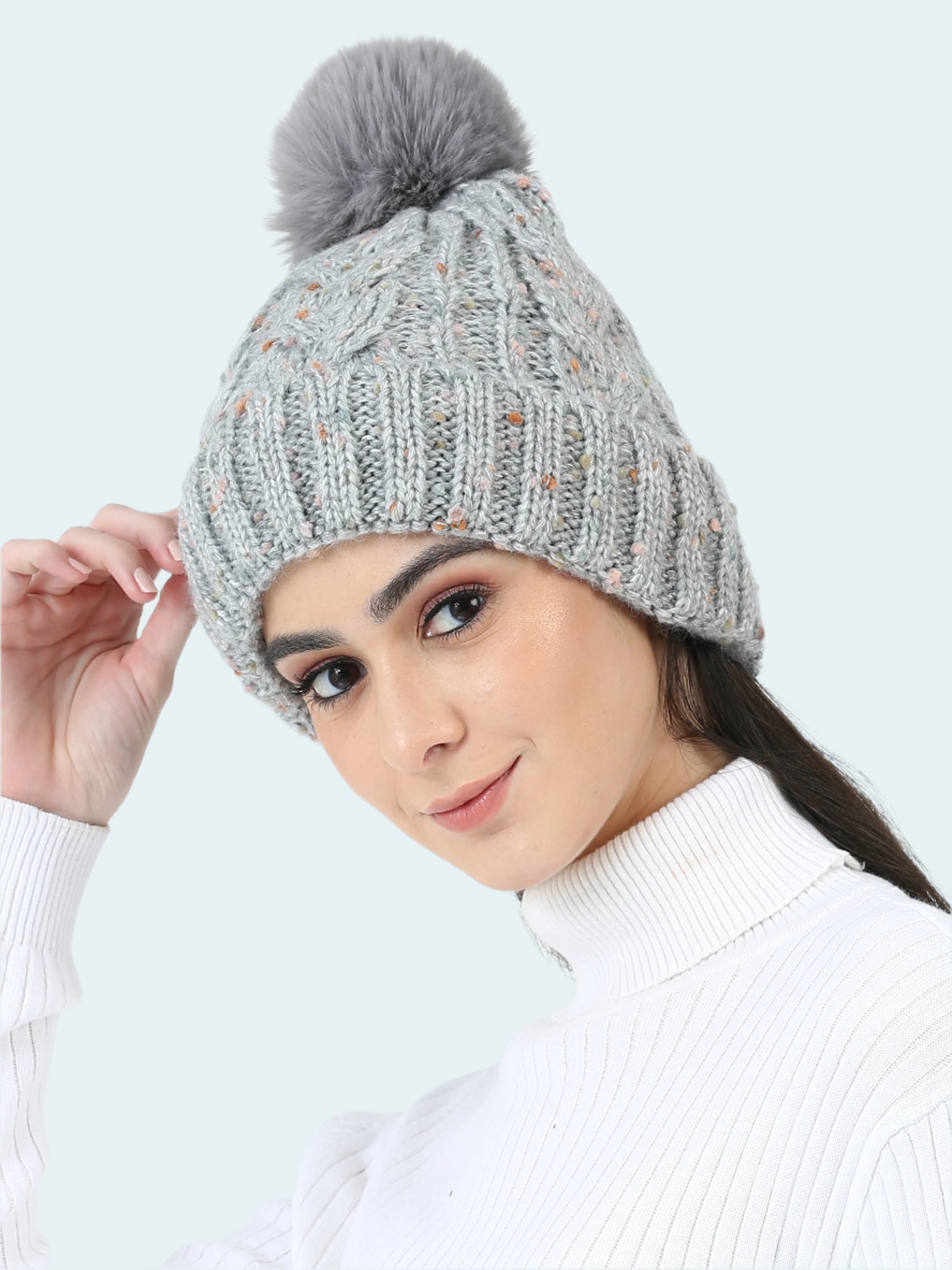 Woman wearing a gray knitted beanie with a pom-pom on a white background