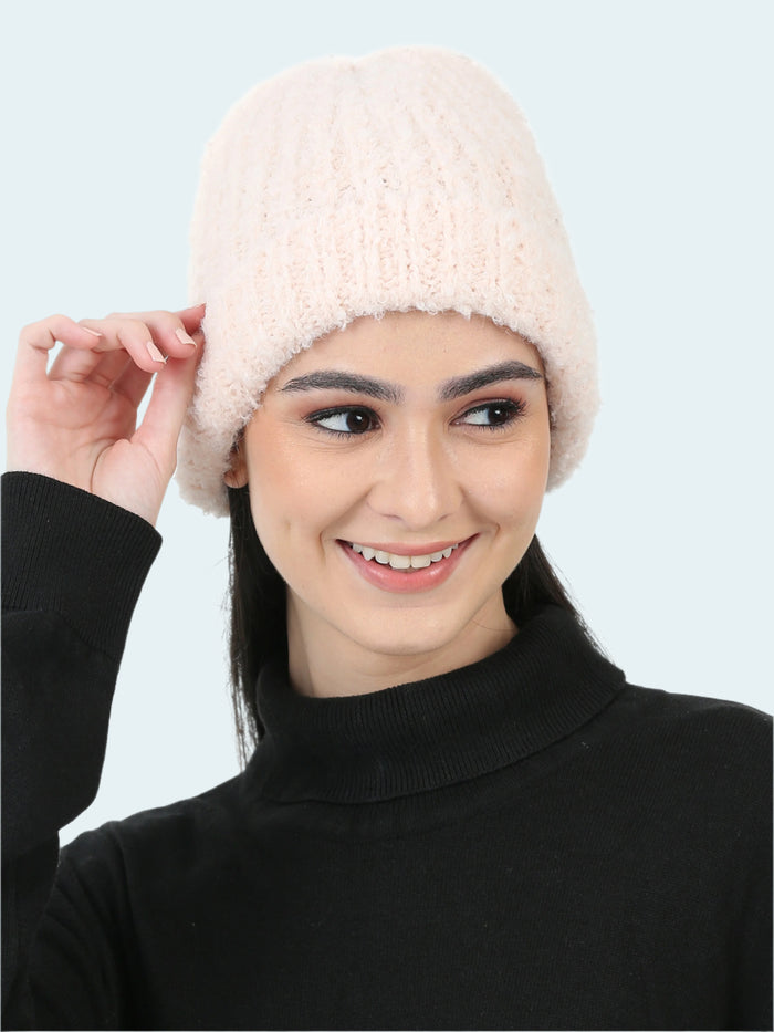 Woman wearing a white knitted beanie against a white background