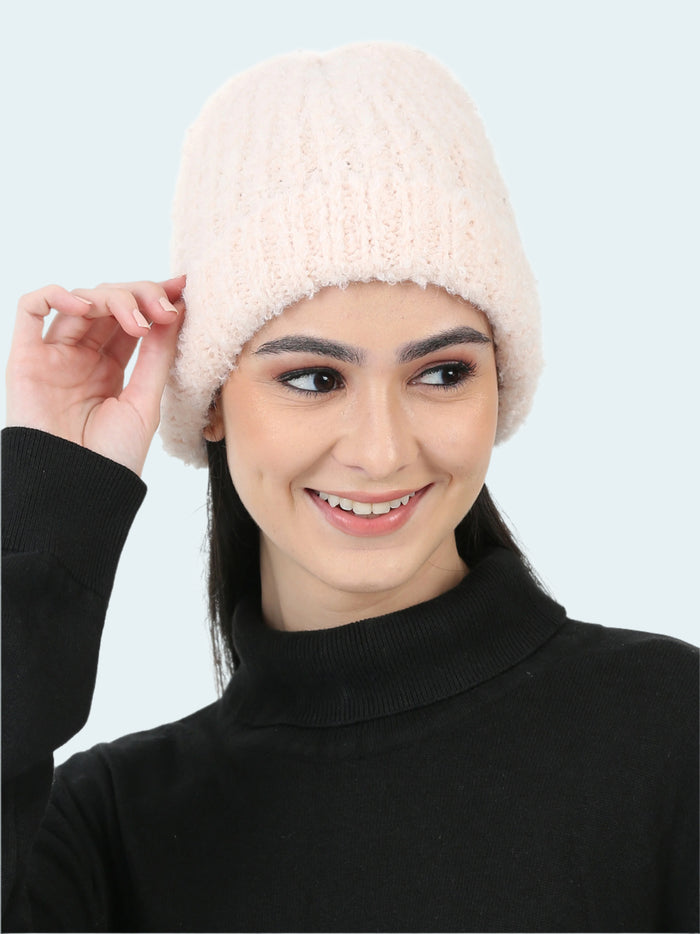 Woman wearing a white knitted beanie against a white background