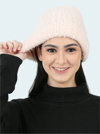 Woman wearing a light pink knitted hat against a white background