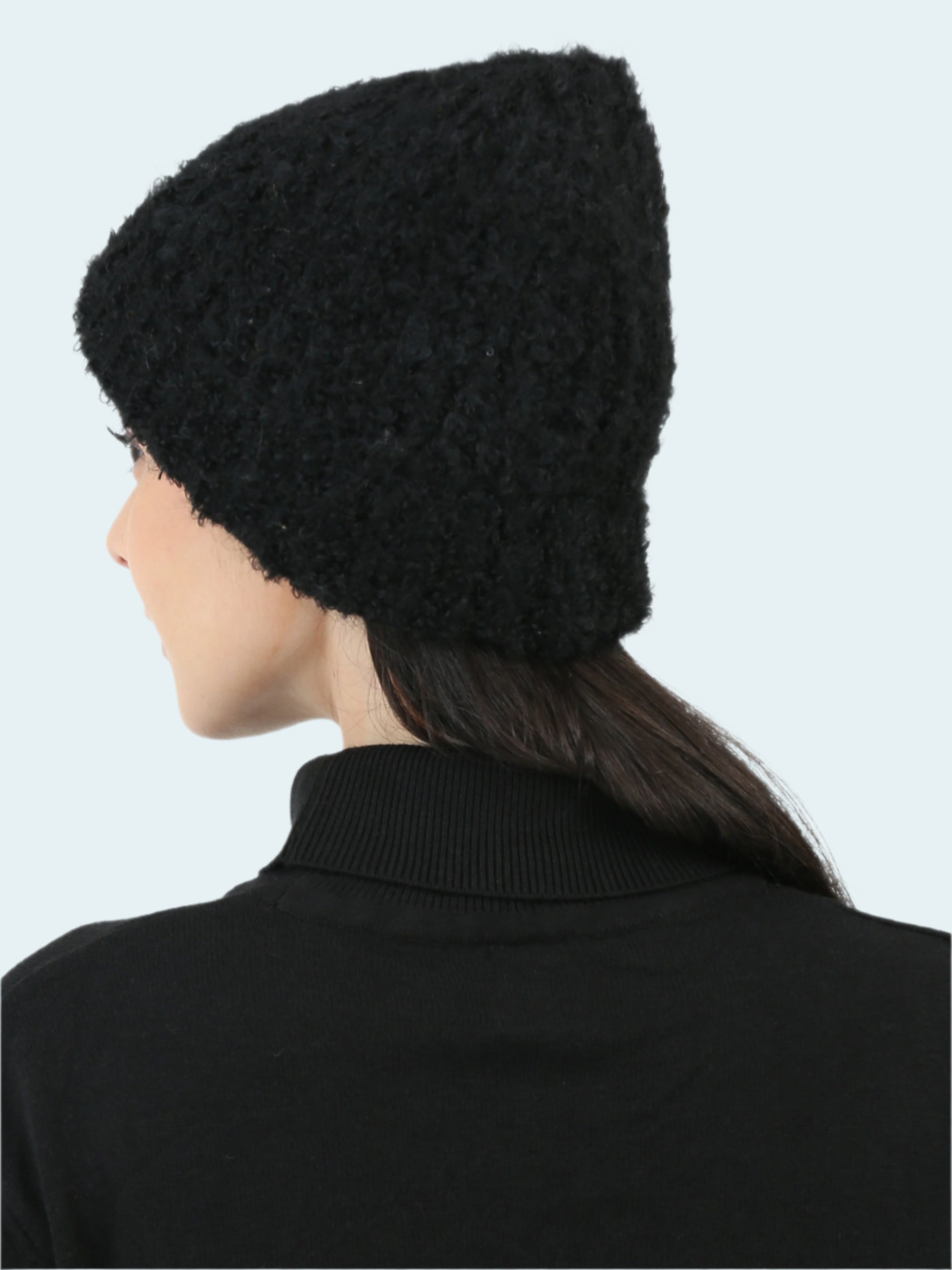 Person wearing a black knitted beanie against a white background