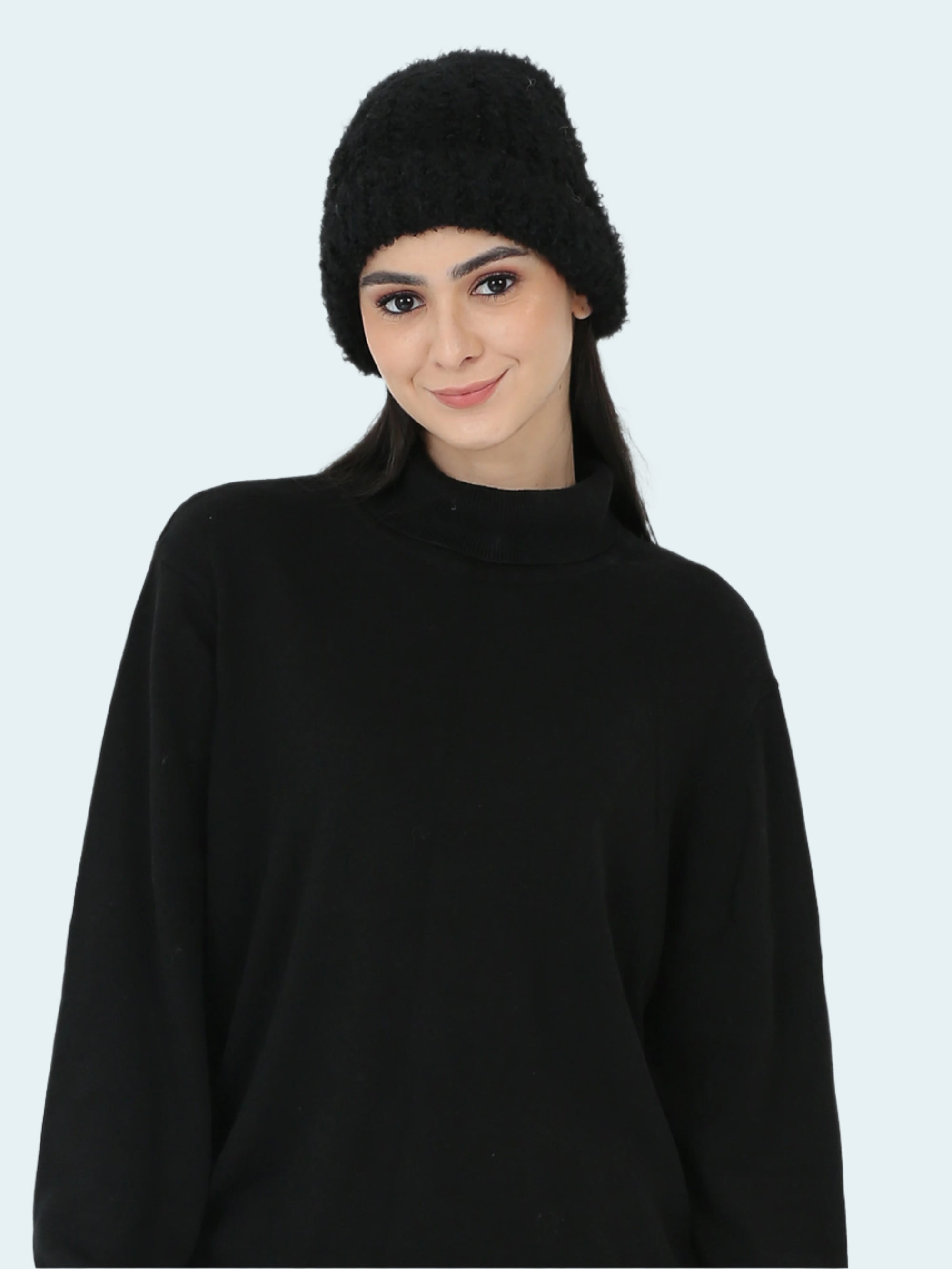 Woman wearing a black knit beanie and sweater against a white background