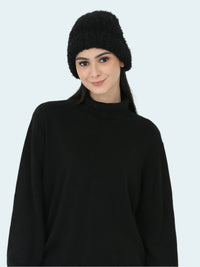 Woman wearing a black knit beanie and sweater against a white background