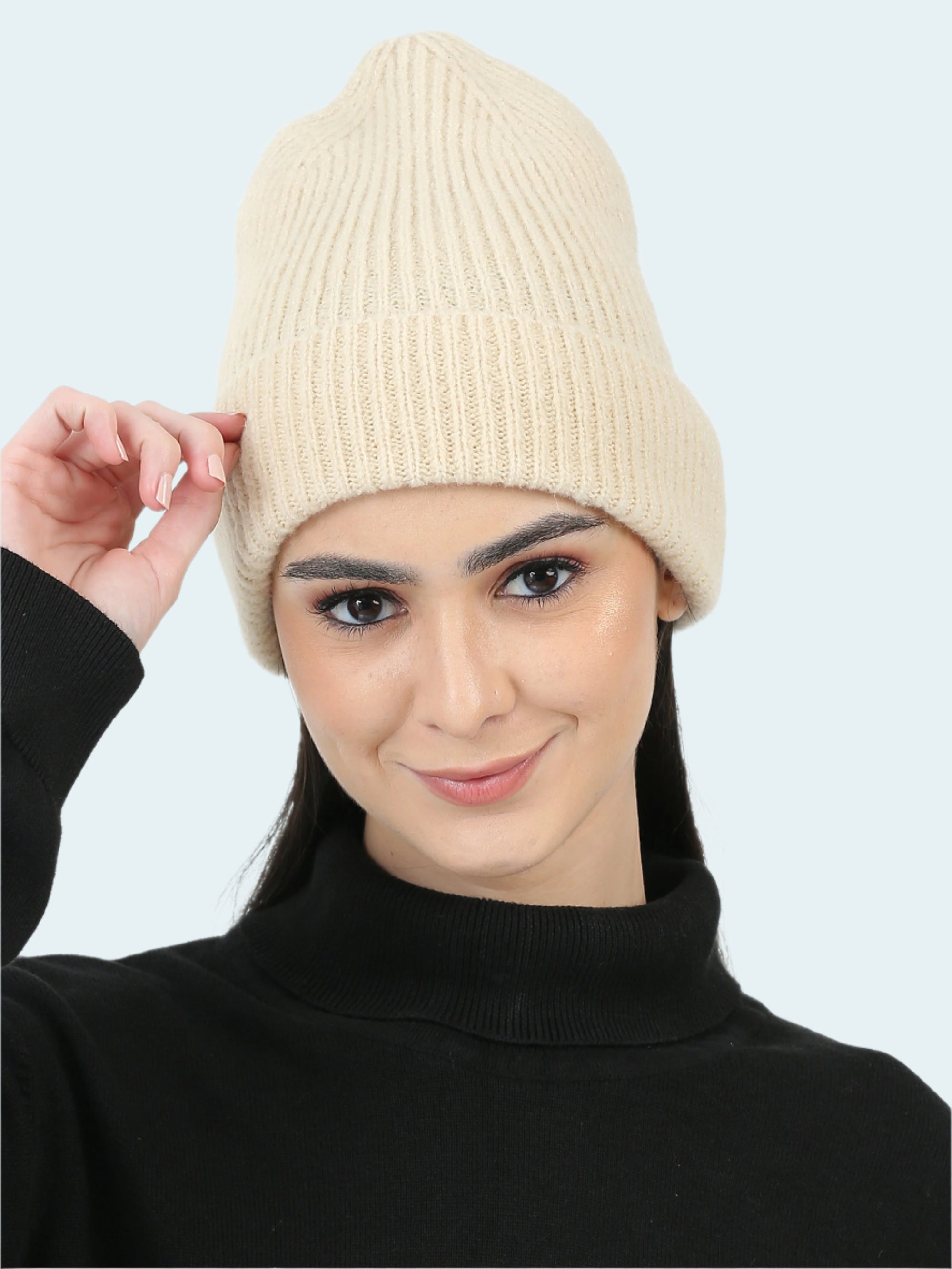 Woman wearing a beige knit beanie against a white background