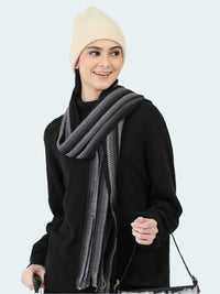 Woman wearing a black outfit with a gray scarf and cream beanie on a white background