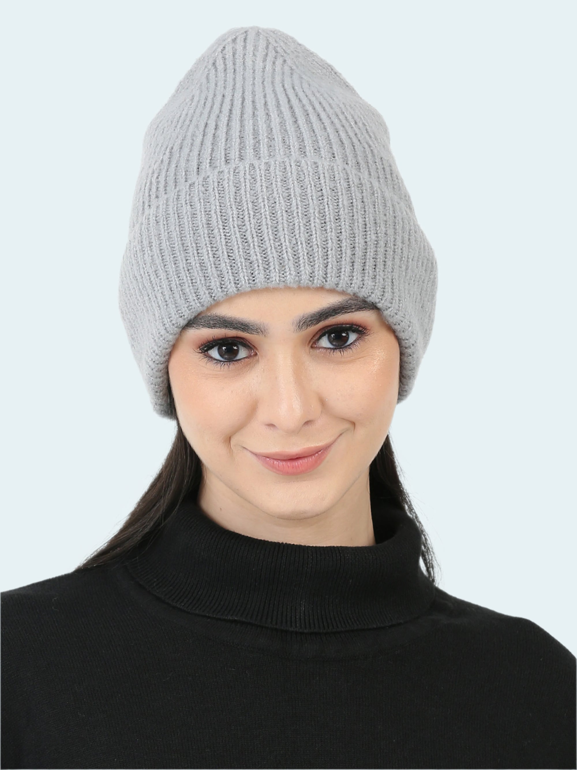 Woman wearing a gray knit beanie on a white background