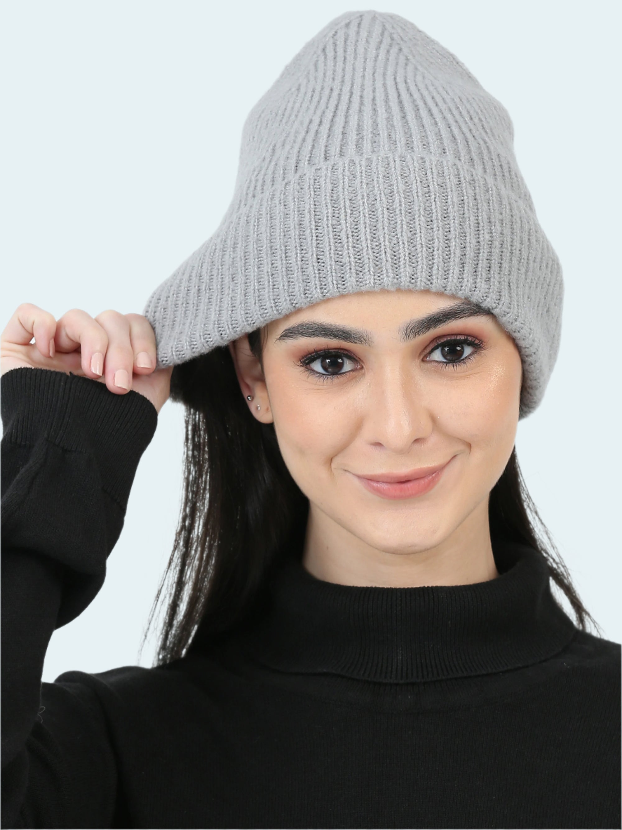 Woman wearing a gray knit beanie against a white background