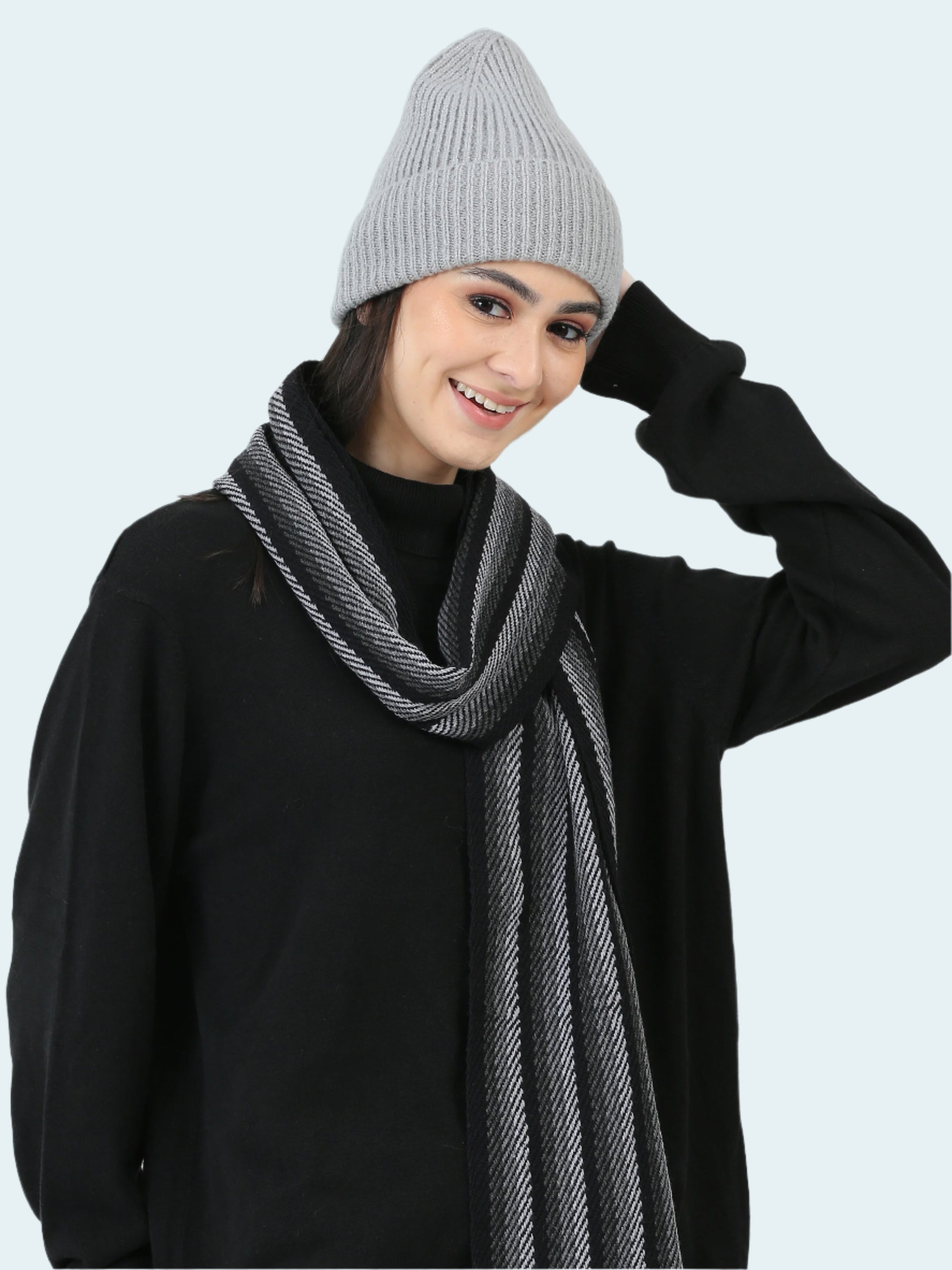 Person wearing a gray knit beanie and scarf on a white background