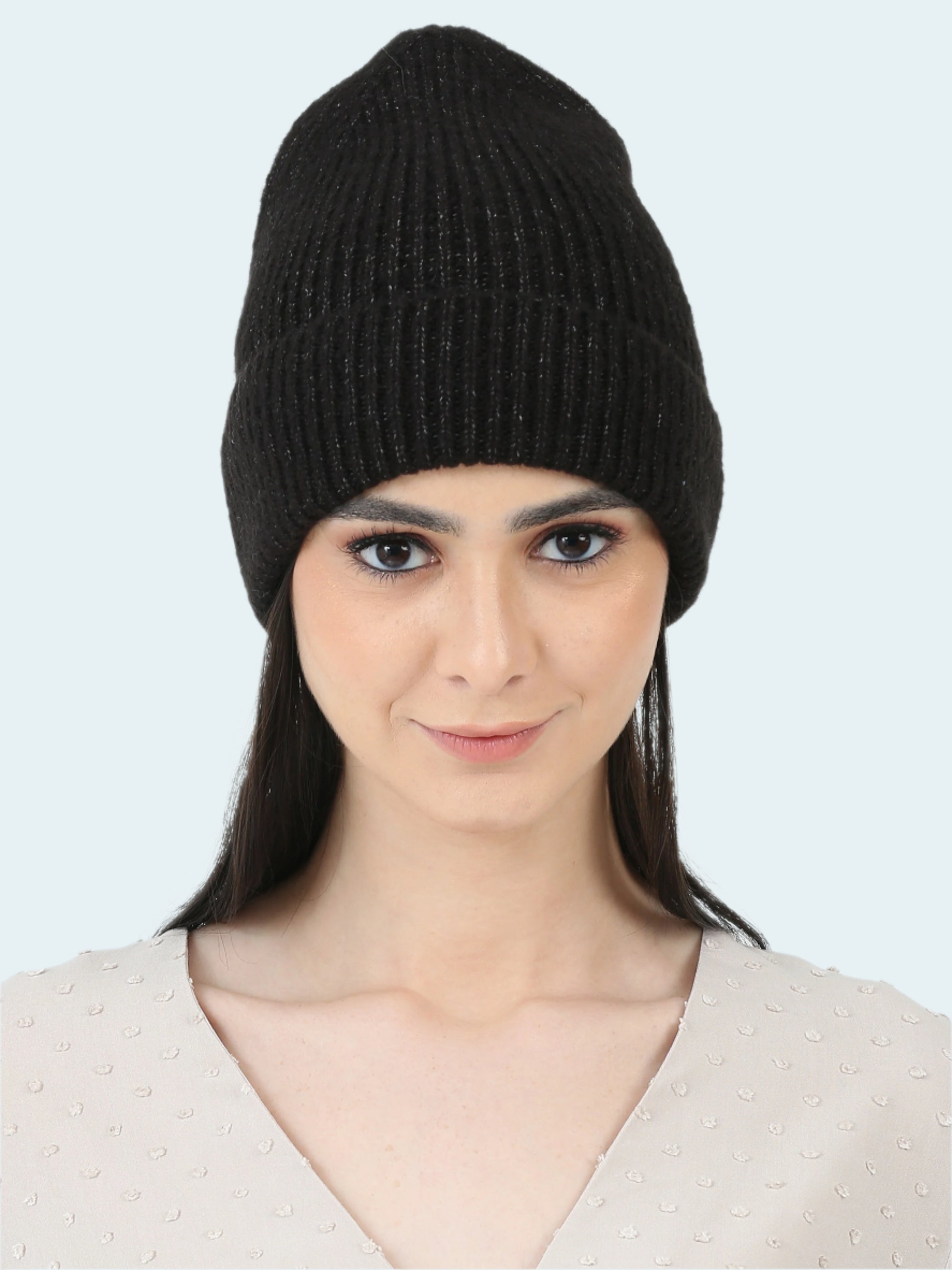 Woman wearing a black knit beanie against a white background