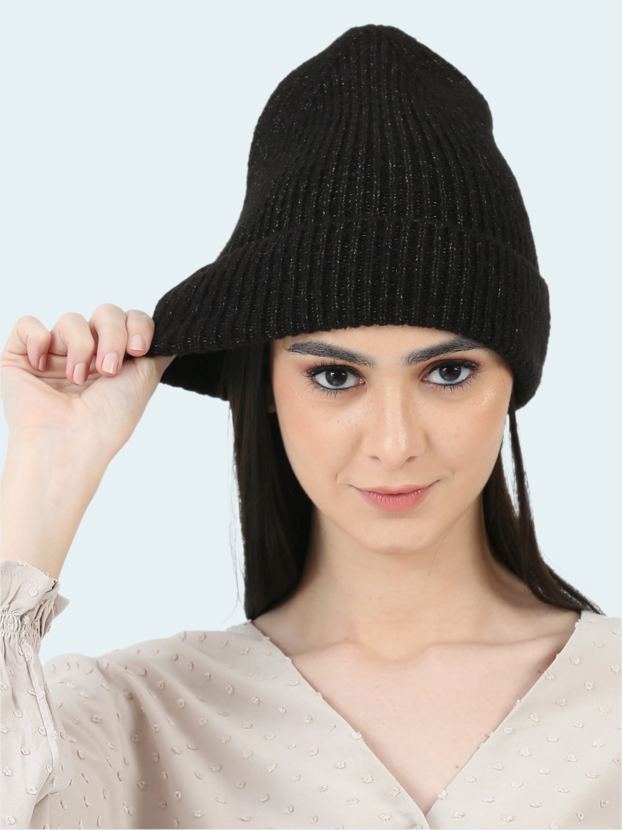 Woman wearing a black knit beanie against a white background