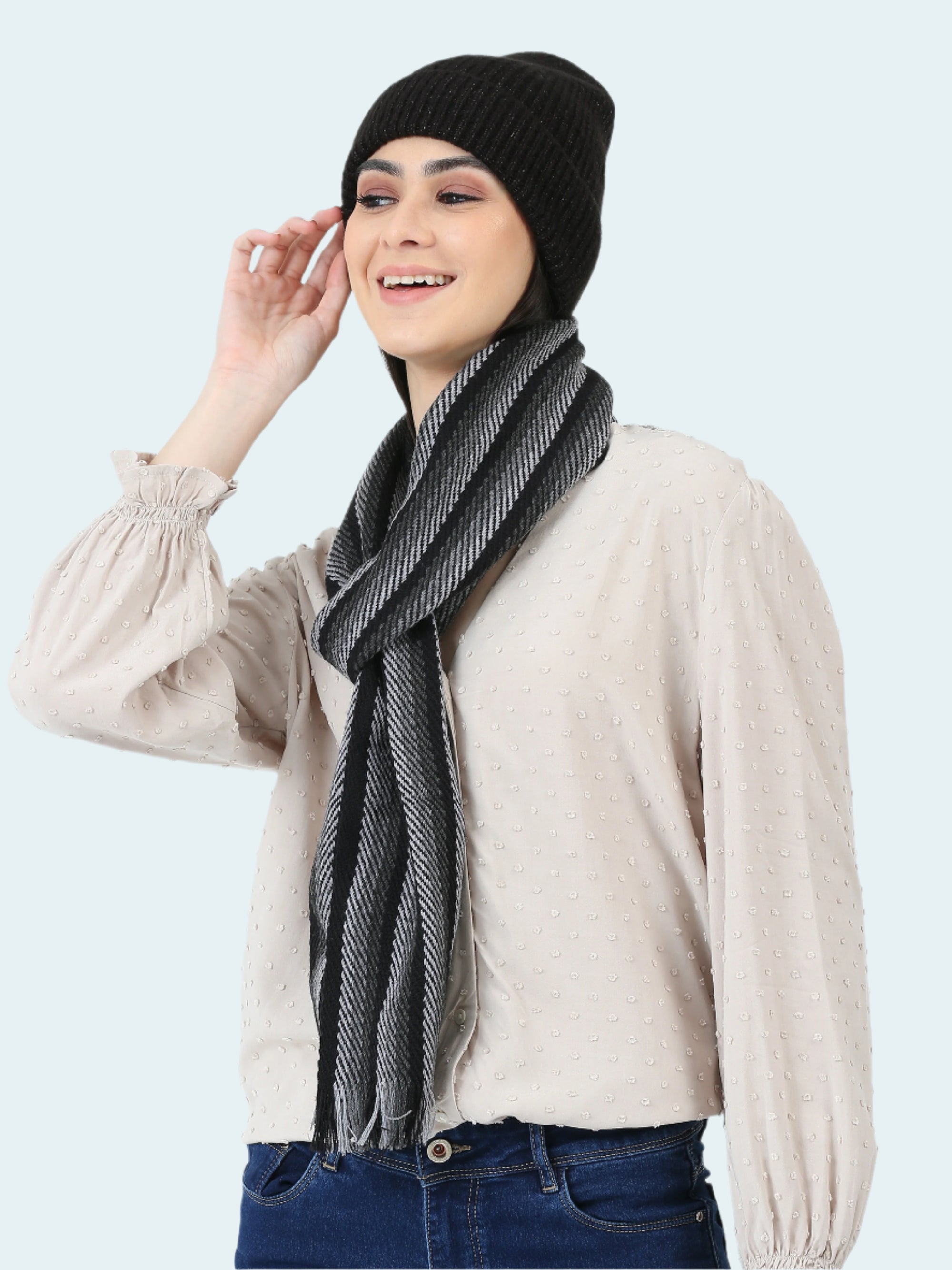Woman wearing a black beanie and scarf with a plain background