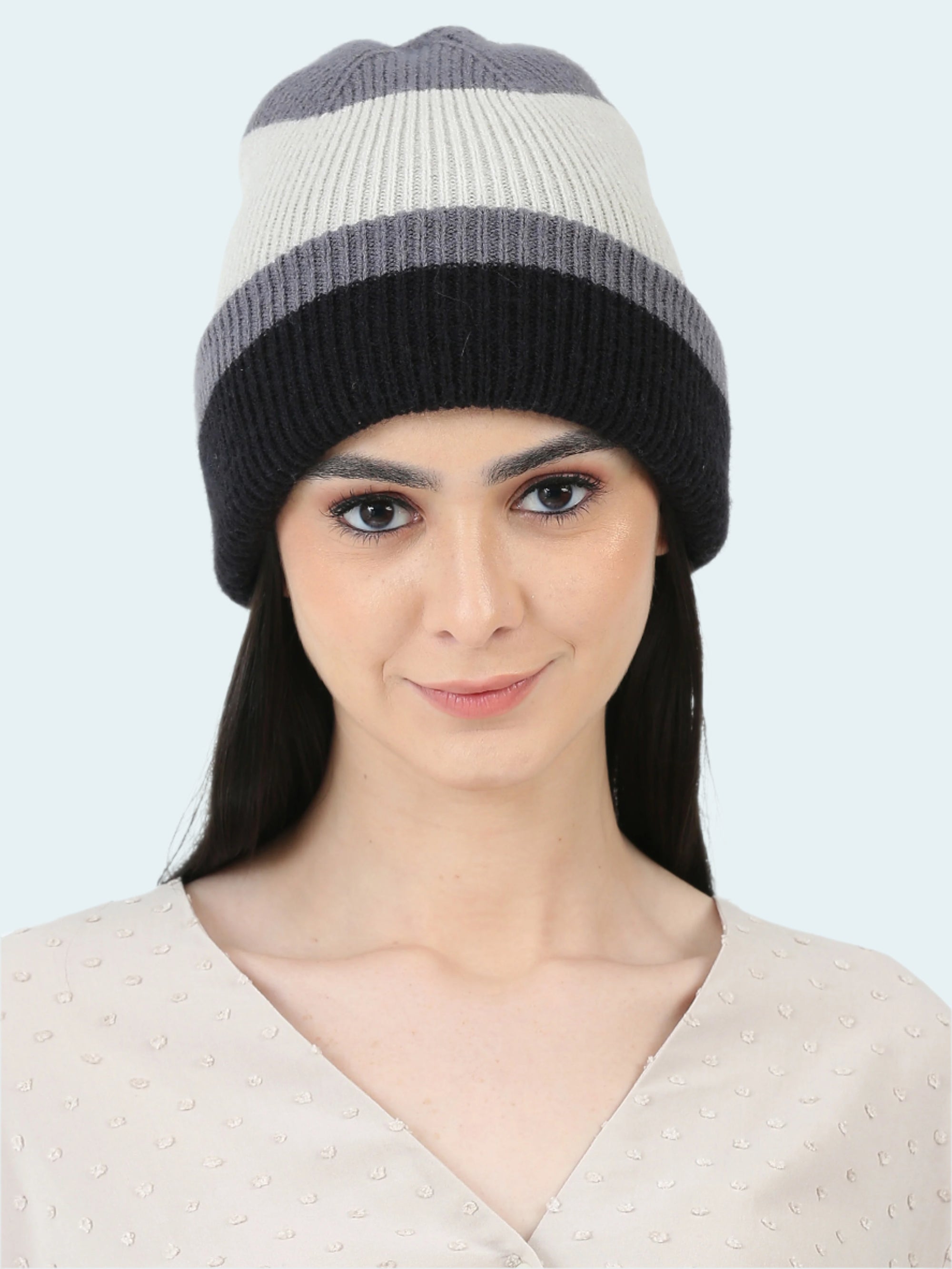 Woman wearing a striped beanie with gray, white, and black colors on a white background