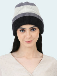 Woman wearing a striped beanie with gray, white, and black colors on a white background