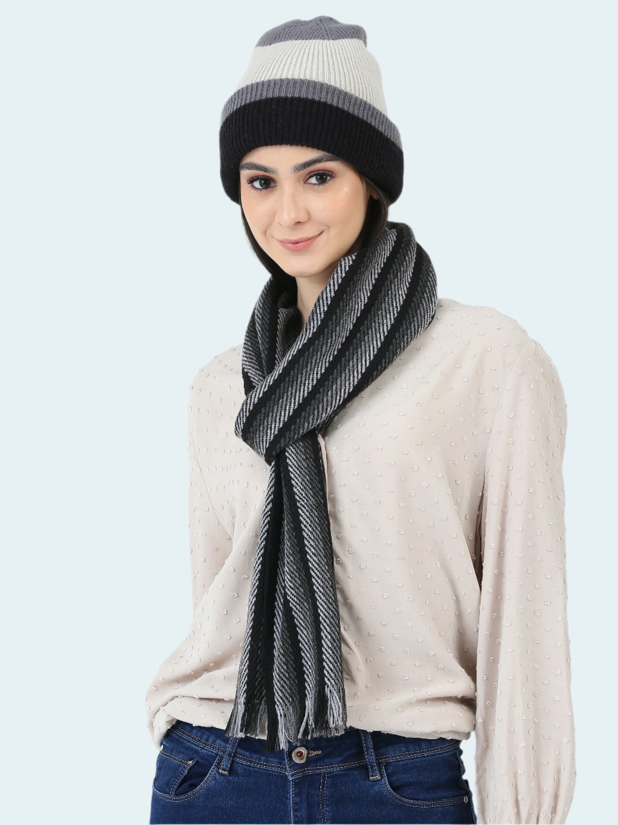 Woman wearing a striped beanie and scarf on a white background