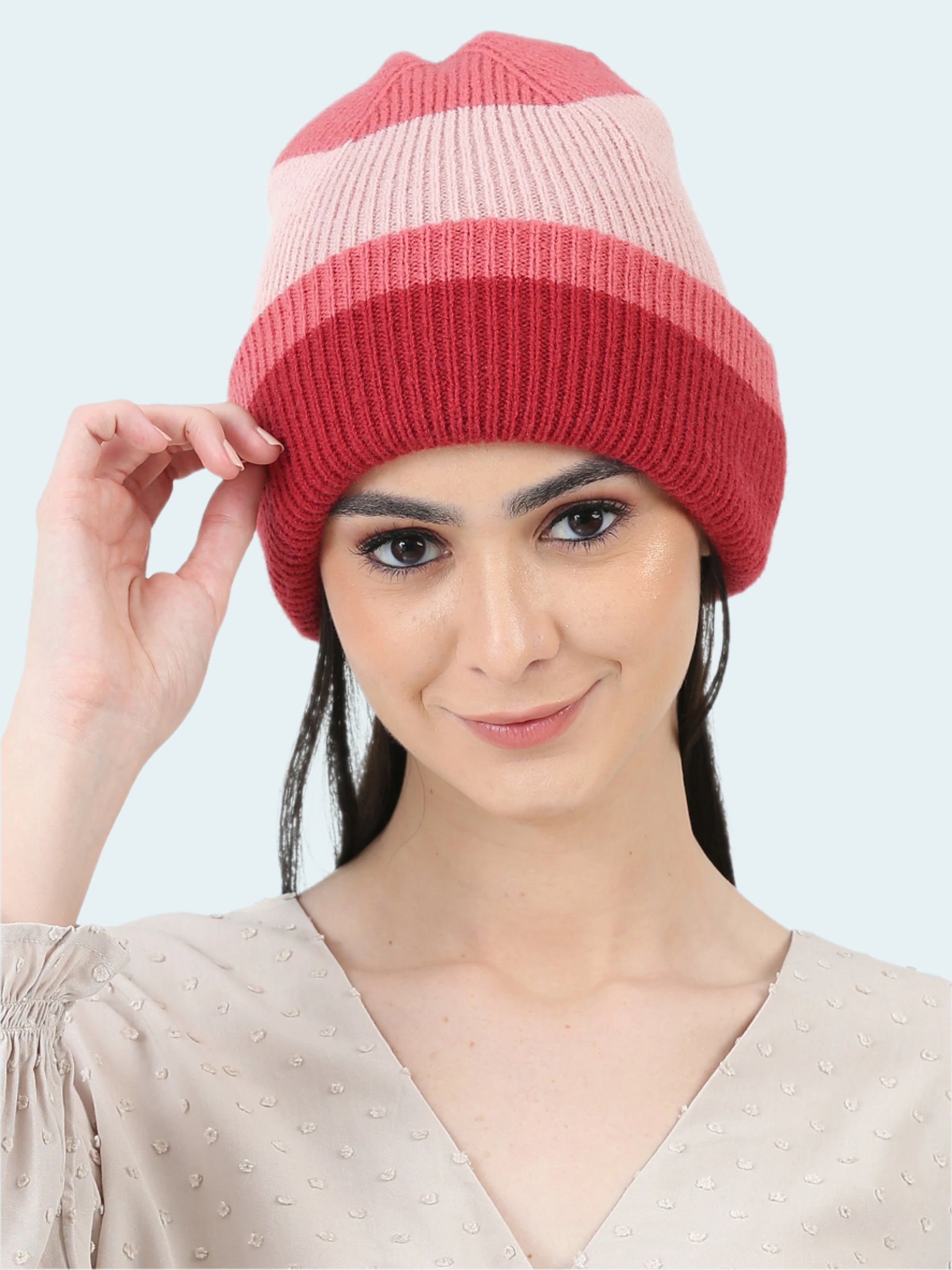 Woman wearing a pink and red striped beanie on a white background