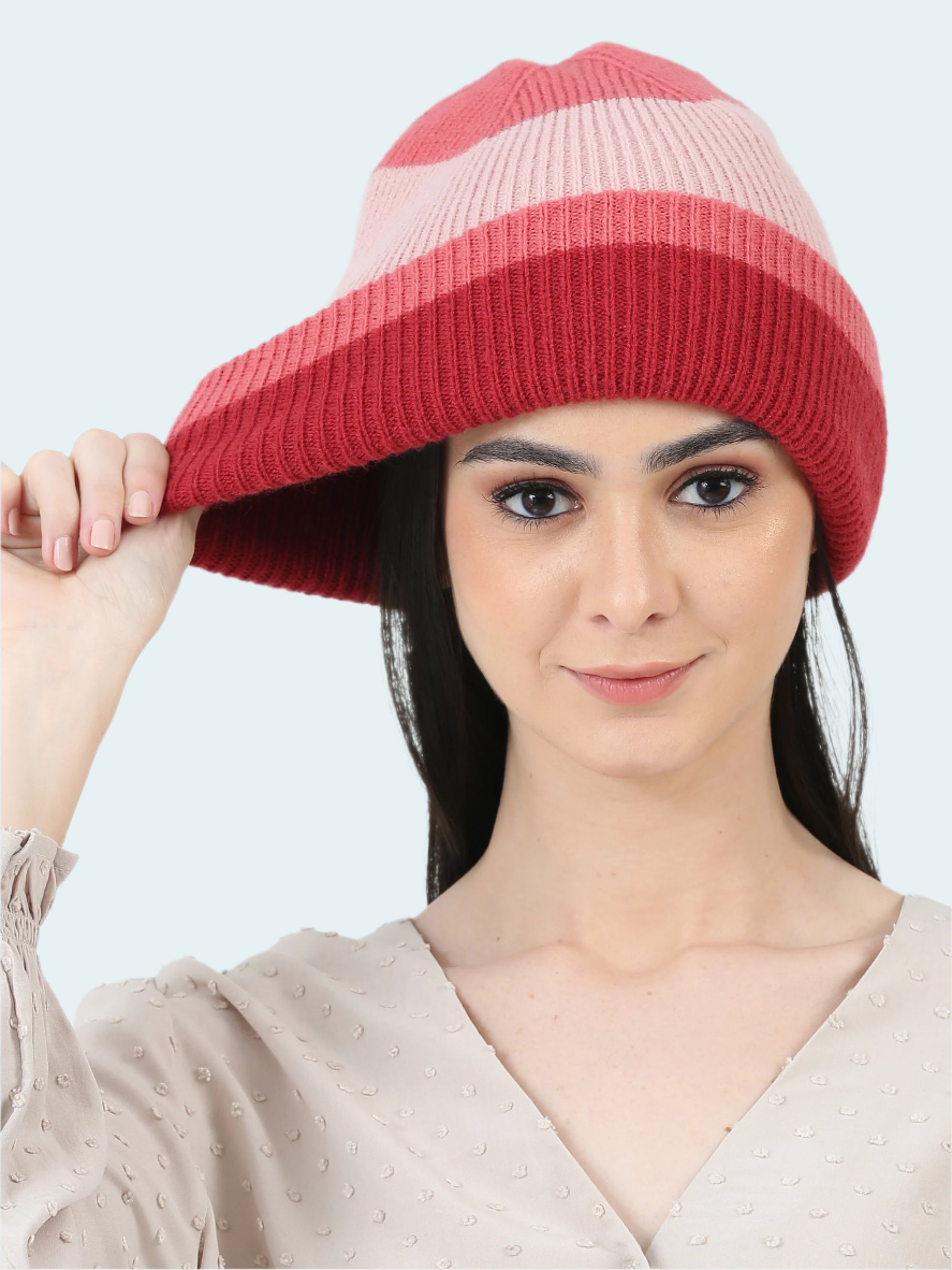 Woman wearing a red and pink striped knit hat against a white background