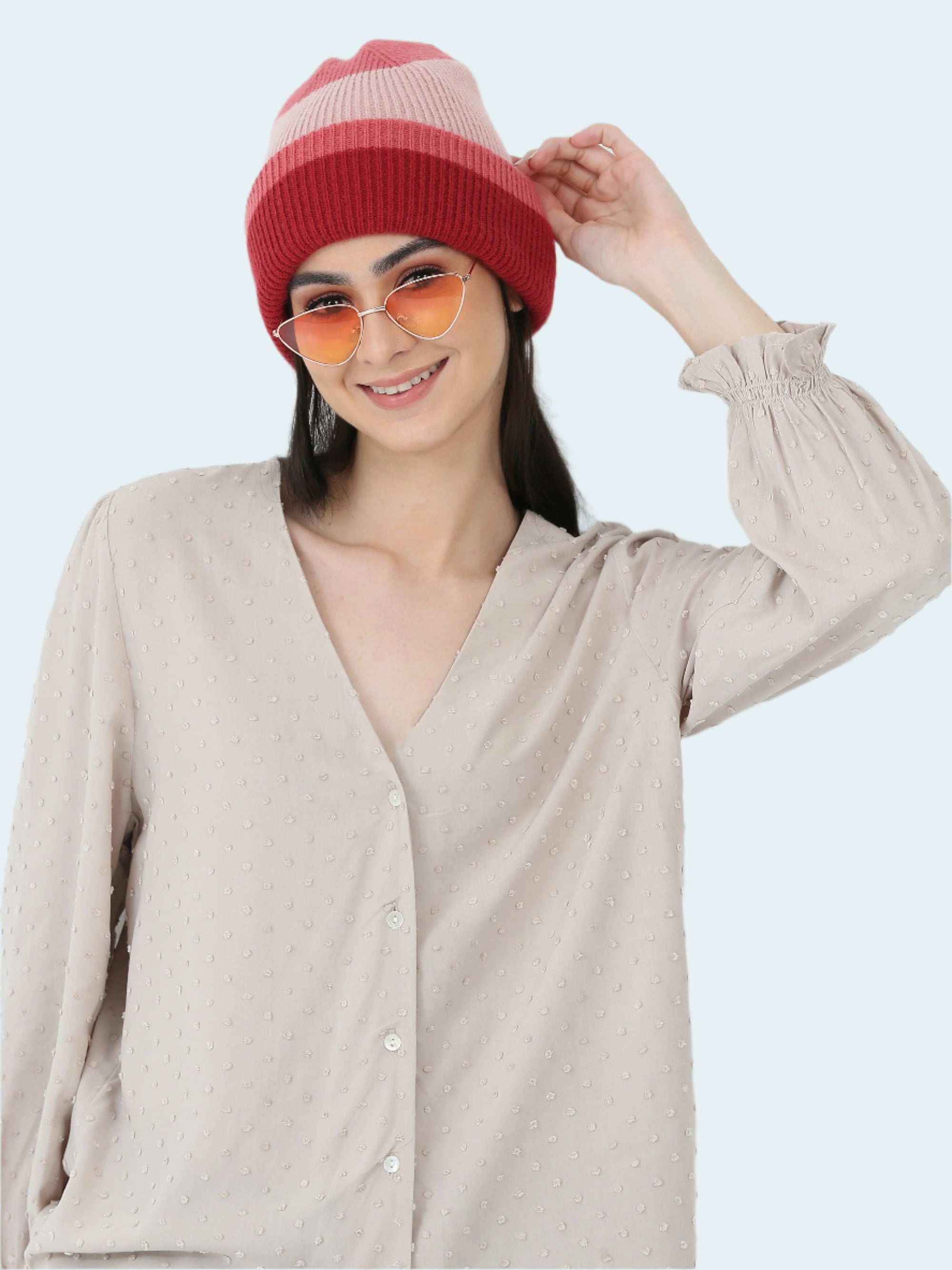 Woman wearing a red beanie and sunglasses against a white background