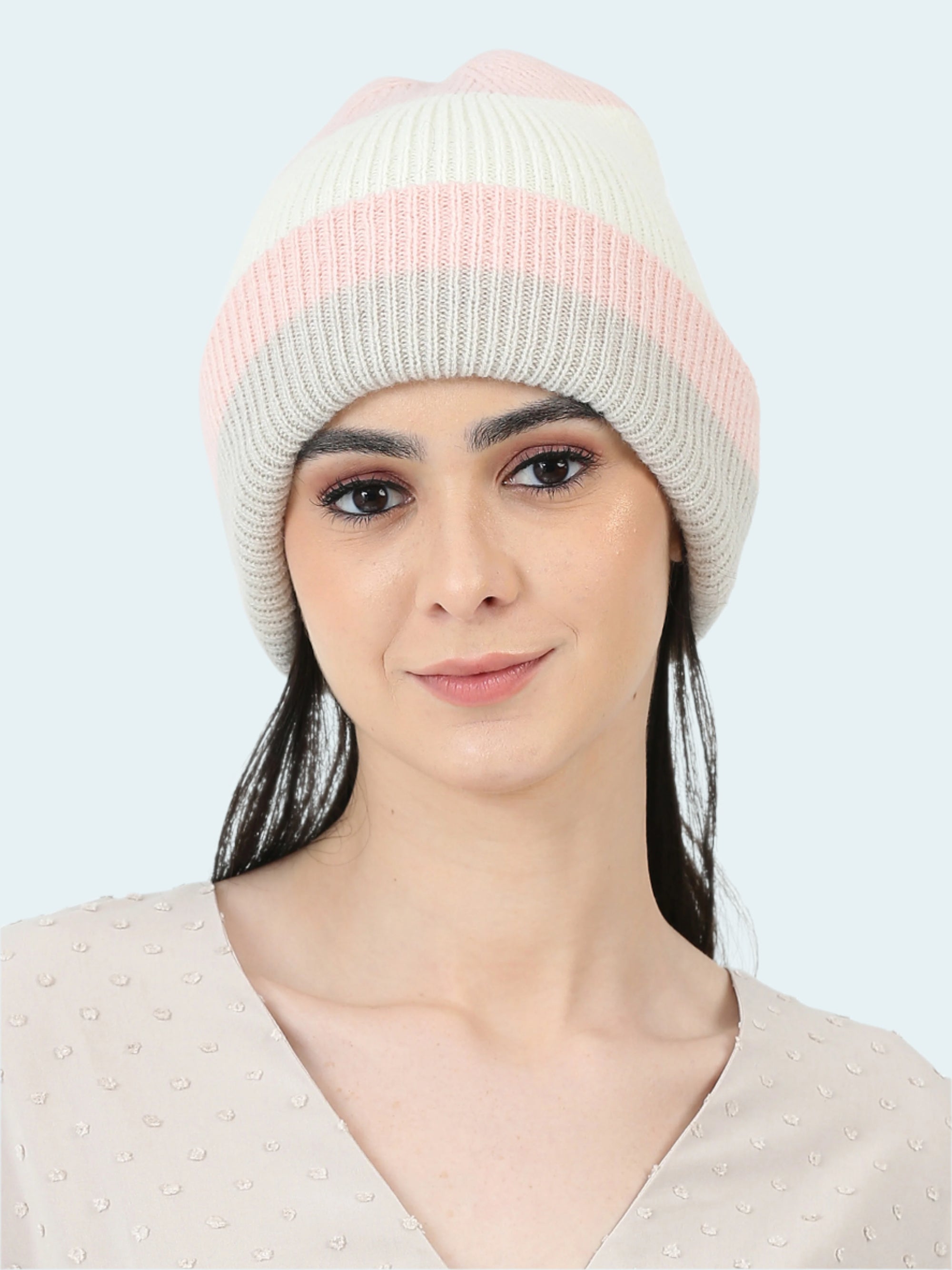 Woman wearing a pink and gray striped beanie on a white background