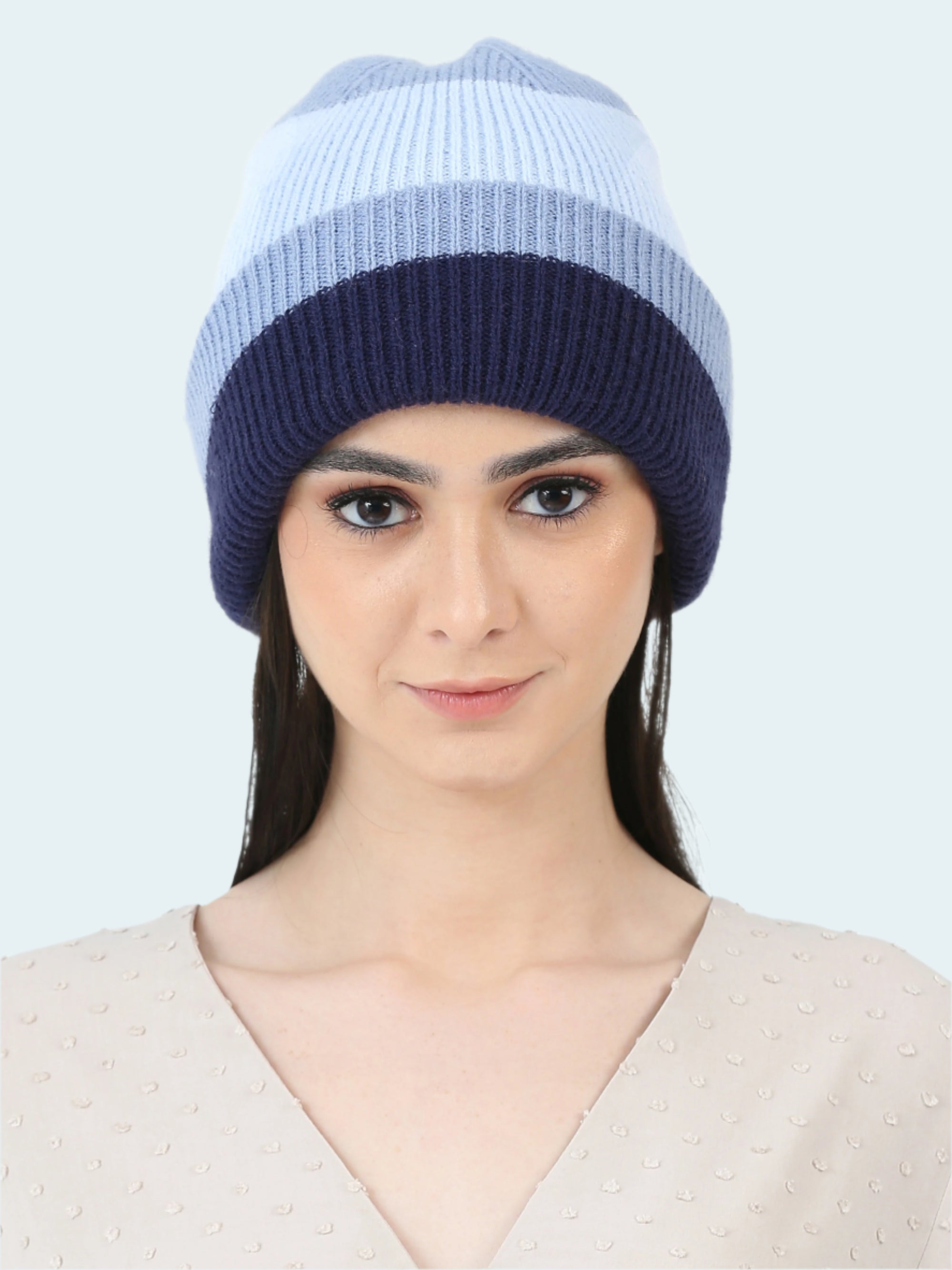 Woman wearing a two-tone blue knit beanie on a white background