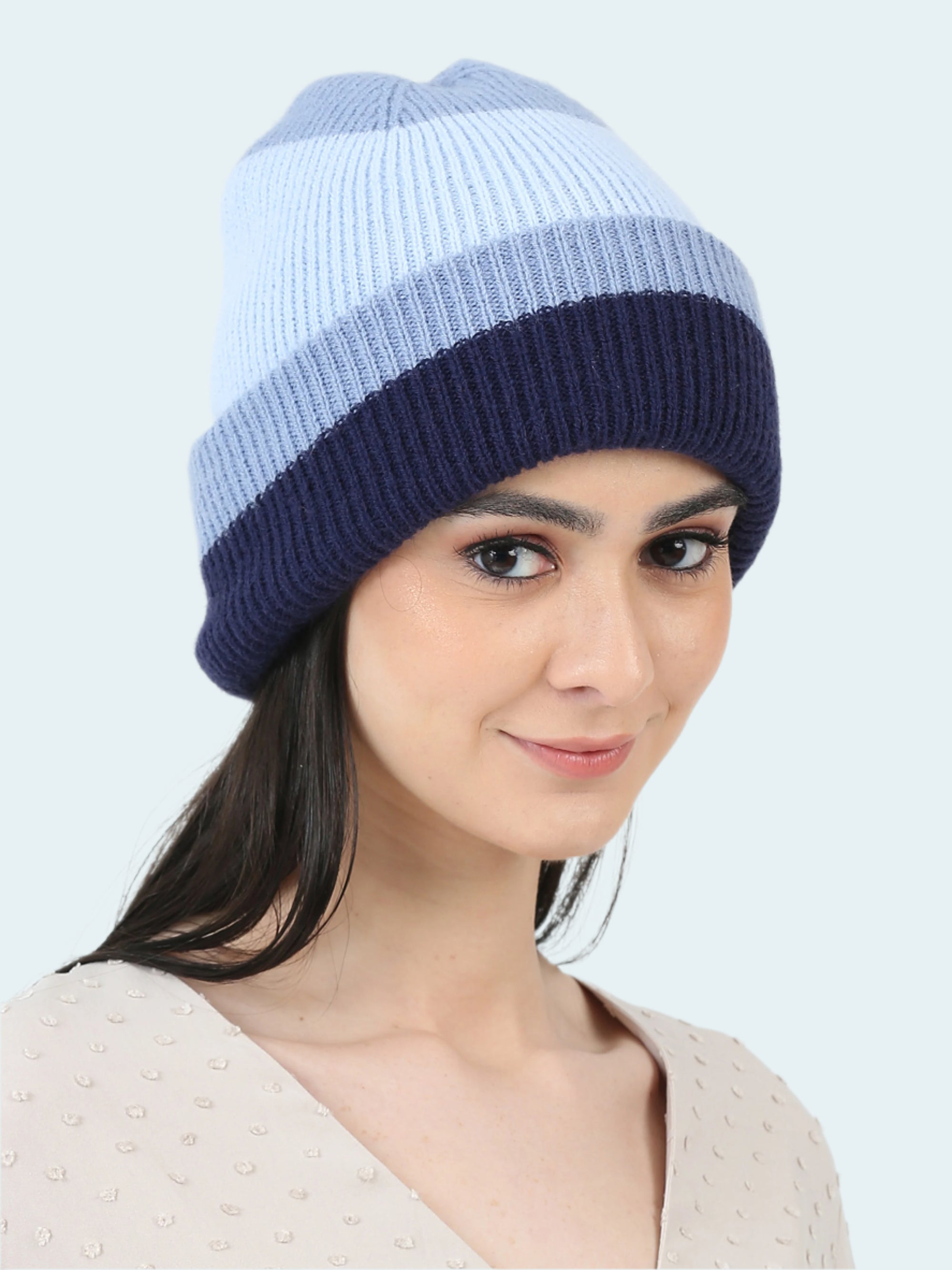 Woman wearing a two-tone blue knit beanie on a white background