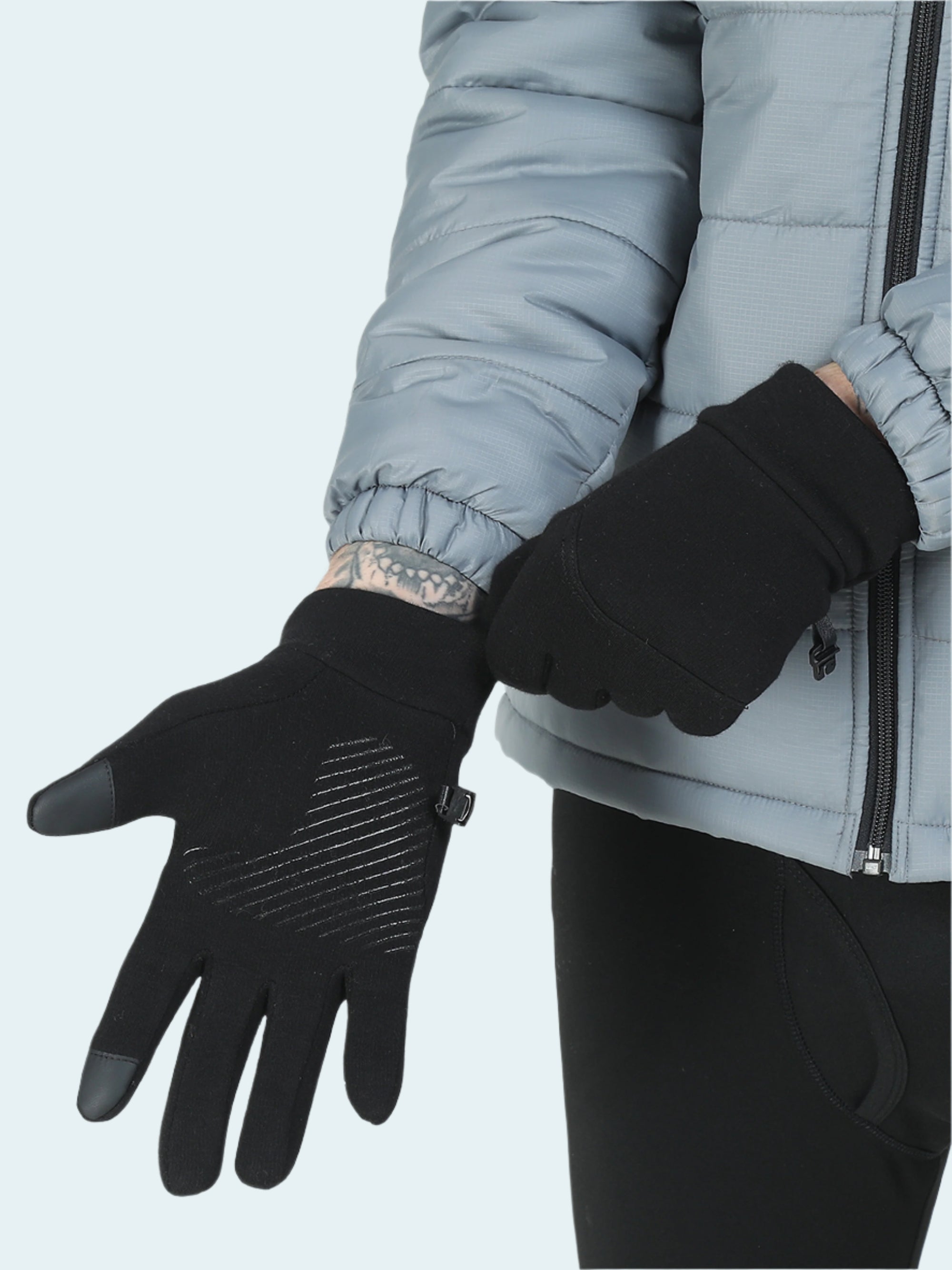 Person wearing black gloves with touch screen tips on a light gray background