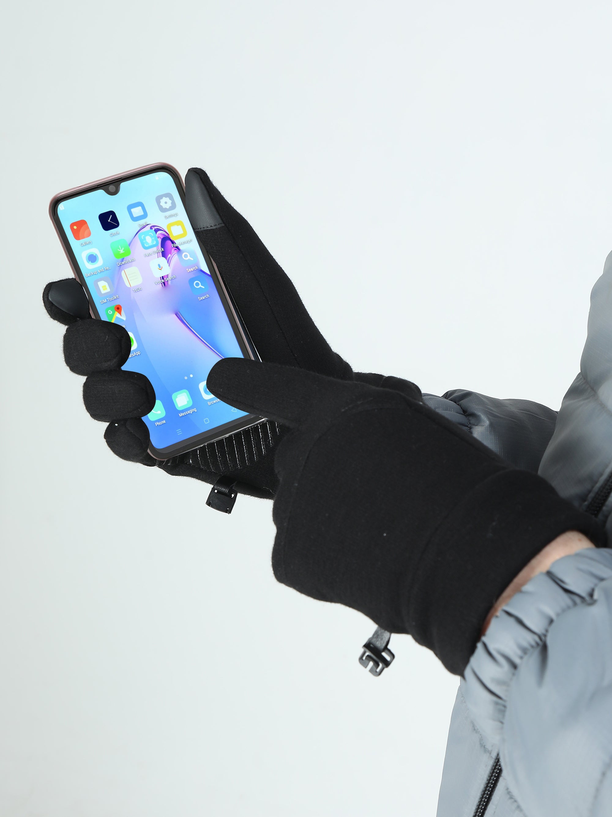 Person wearing black gloves holding a smartphone with a white background