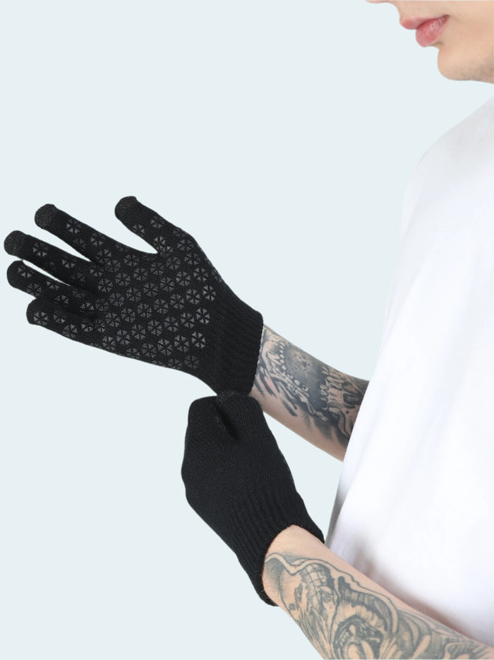 Black gloves with textured palm held by a person with tattoos on a white background