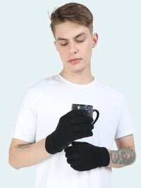 Person wearing black gloves holding a mug against a white background