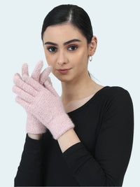 Woman wearing pink fuzzy gloves against a white background