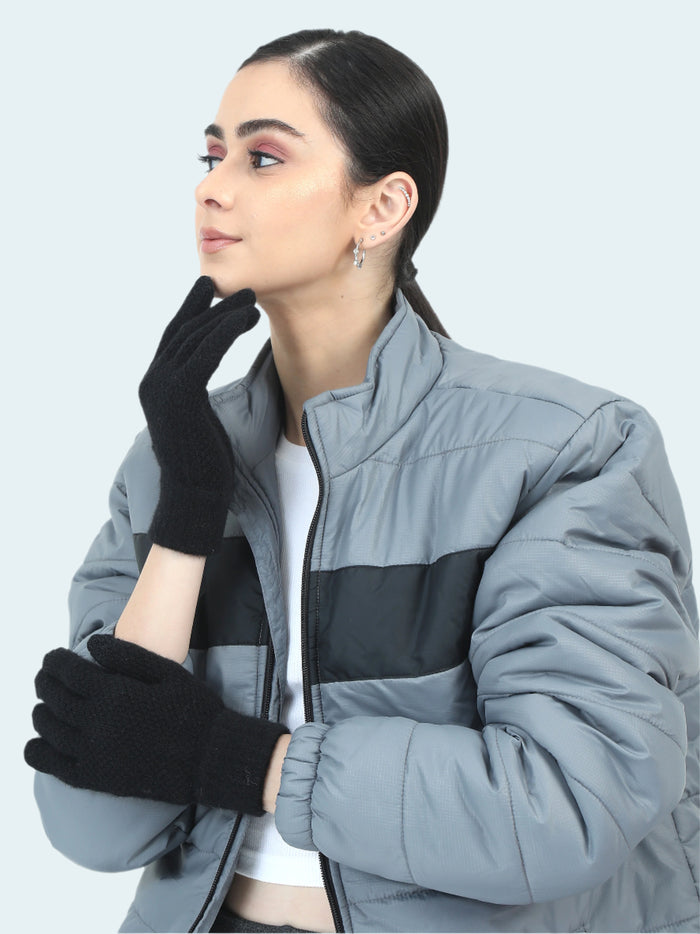Woman wearing a gray and black jacket with black gloves on a white background