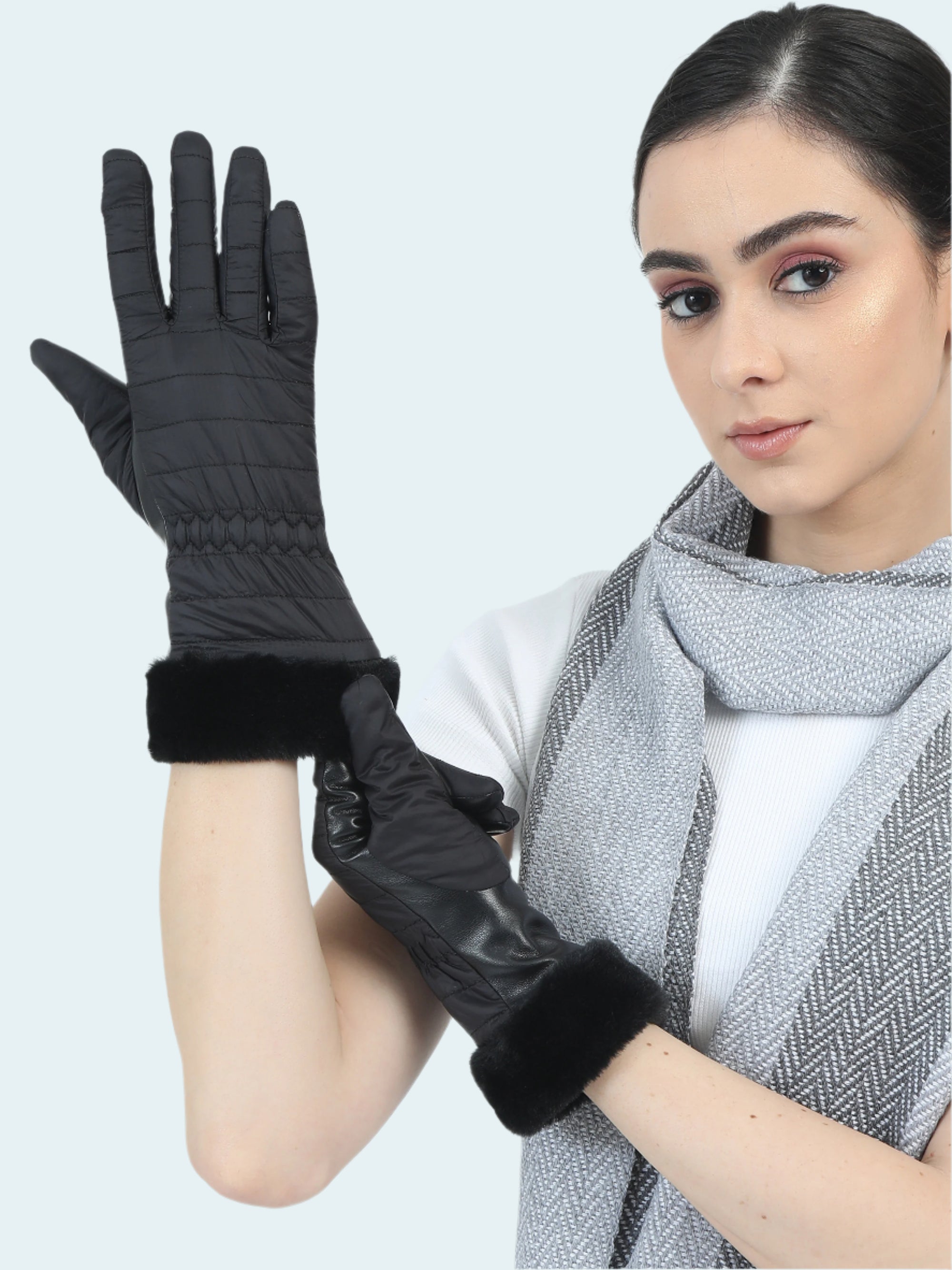 Woman wearing black gloves with fur cuffs on a white background