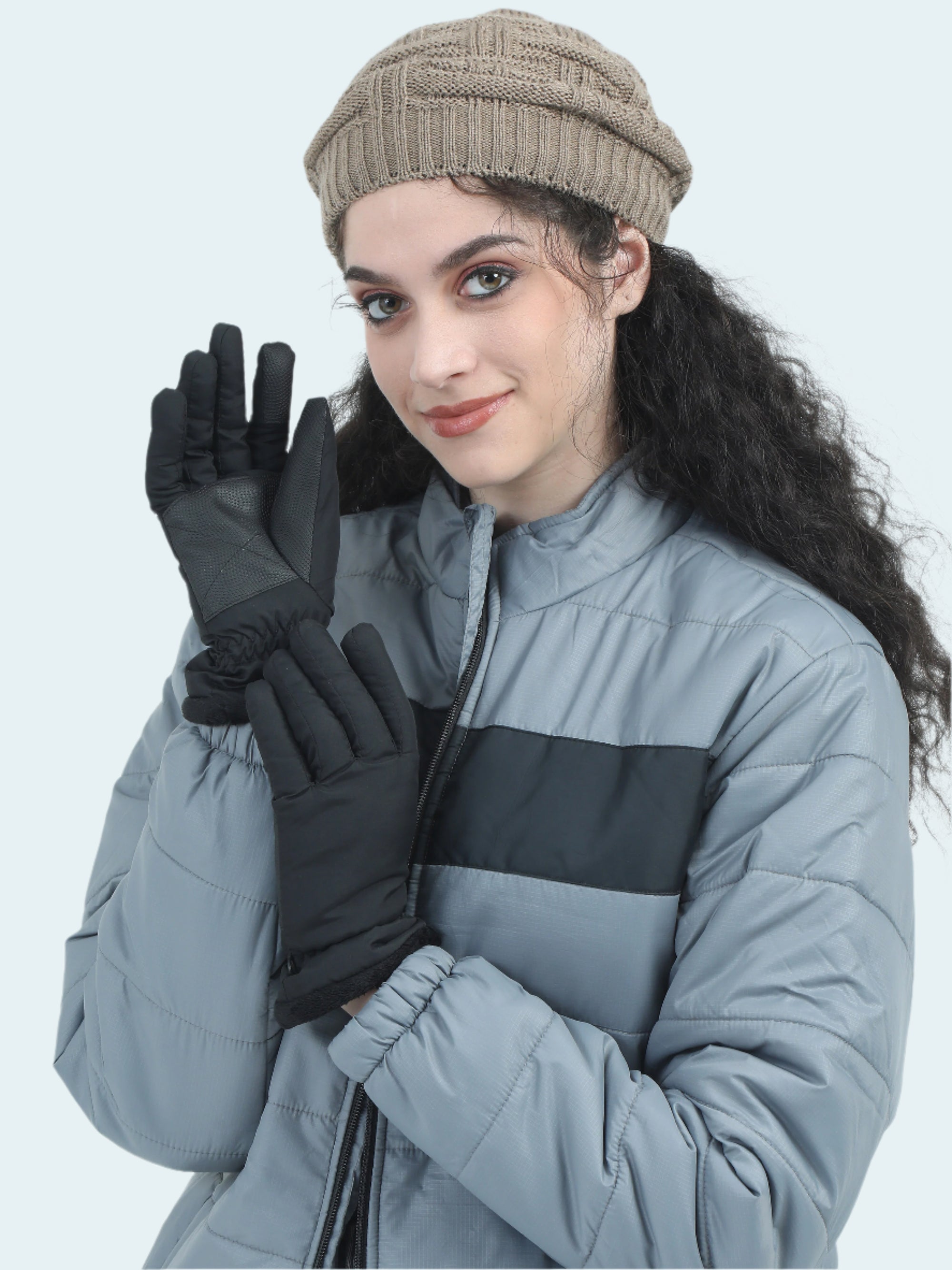 Person wearing a gray jacket, black gloves, and a beige beanie on a white background