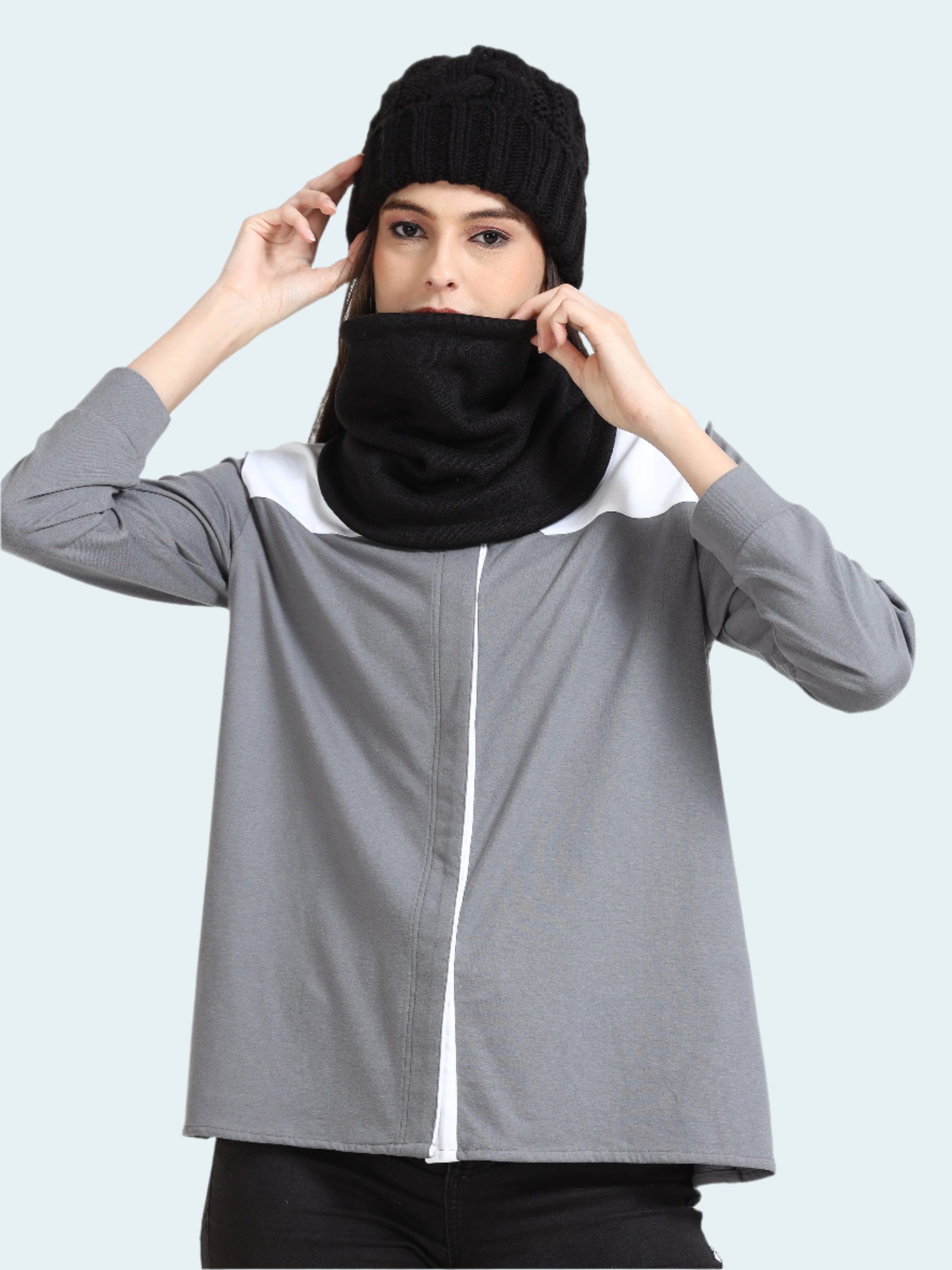 Person wearing a gray jacket with a black hood and gaiter on a white background
