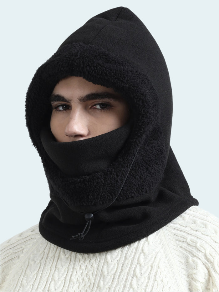 Person wearing a black balaclava against a light gray background